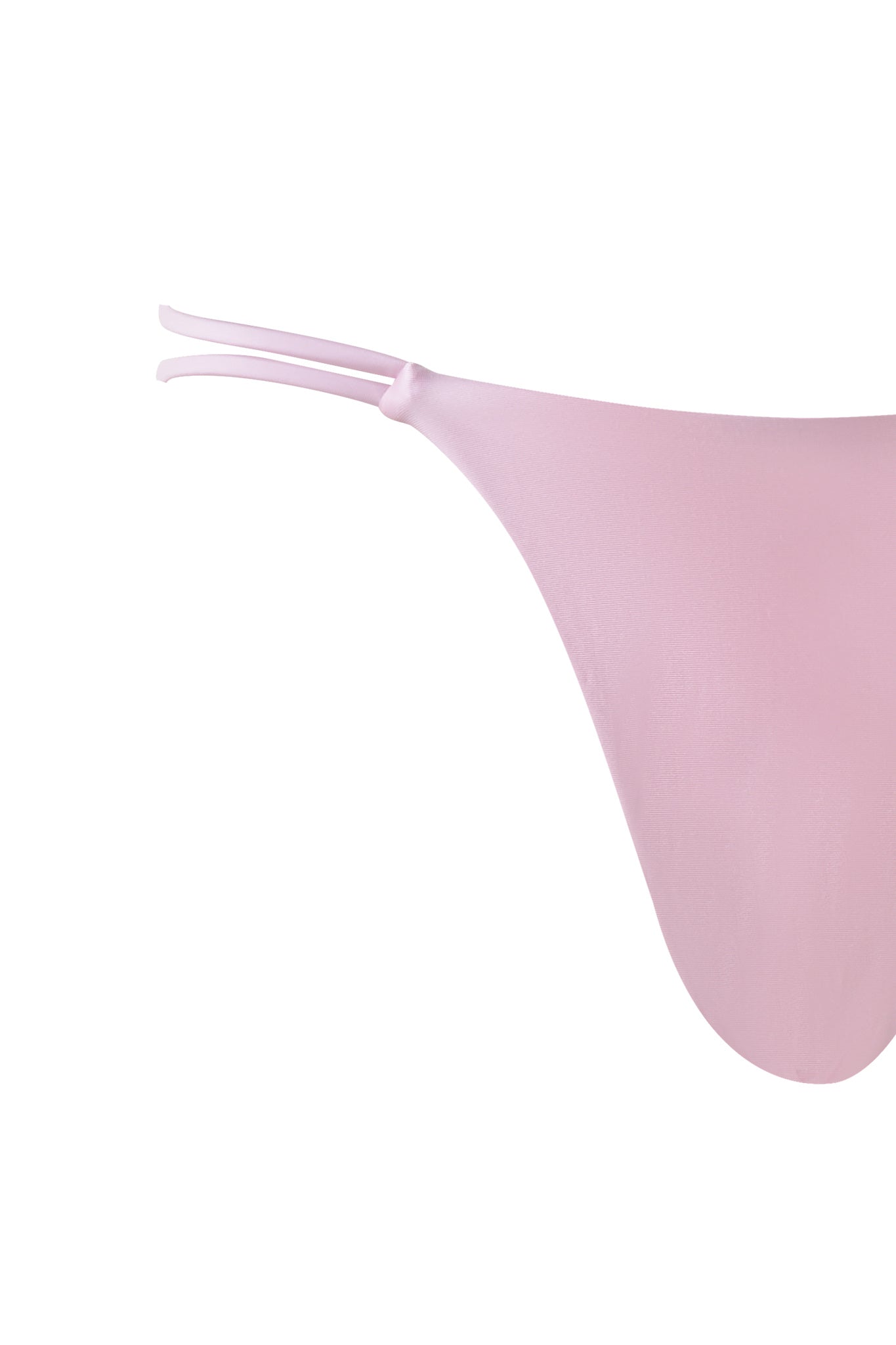A close-up view of the pastel pink PUKA BIKINI BOTTOM from I.AM.GIA reveals its thong-style design with thin double side straps. The smooth, stretchy fabric highlights the minimalistic design and delicate color of this swimsuit.