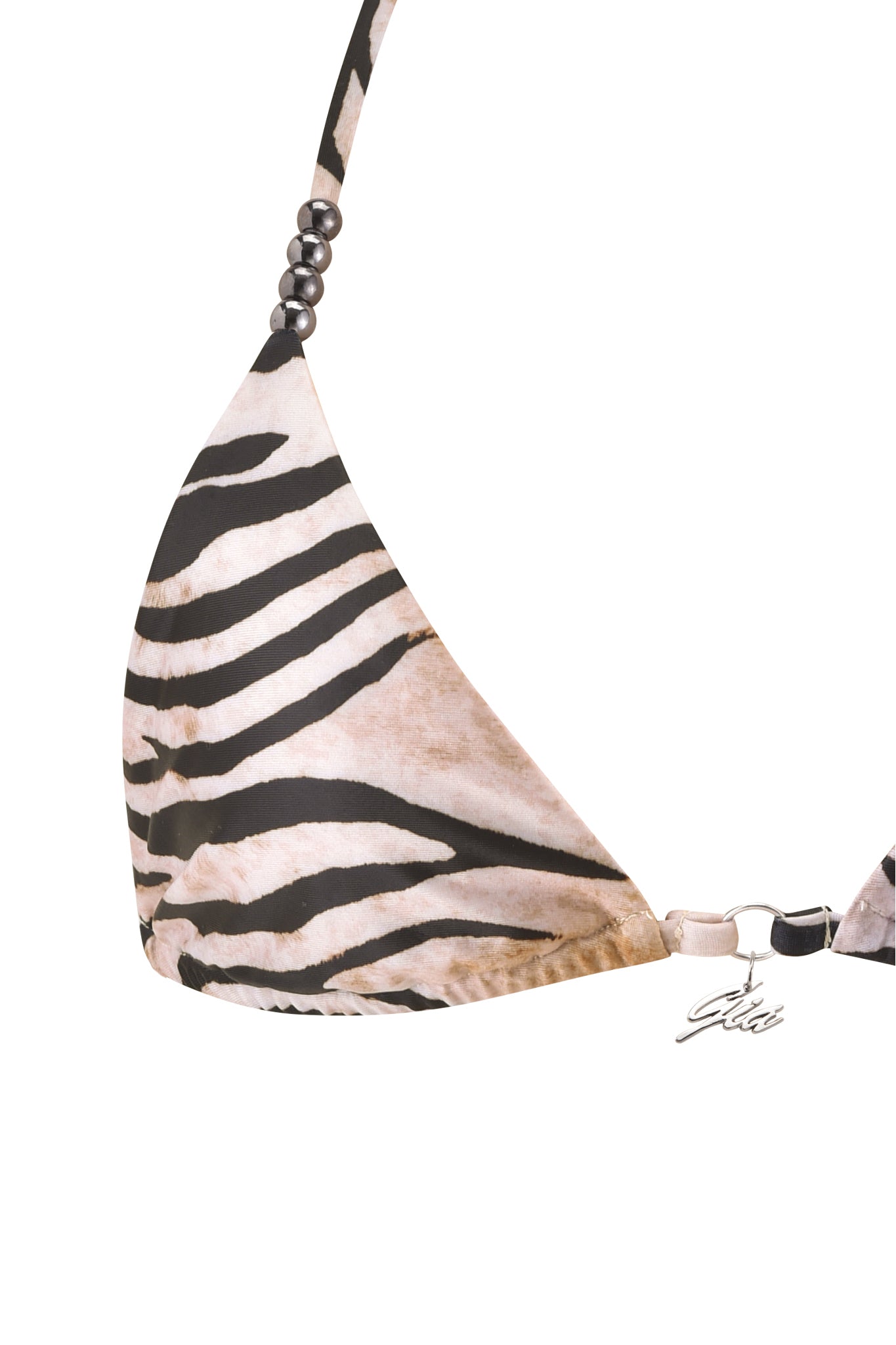A close-up of the I.AM.GIA LUMANI BIKINI TOP - WILD SIDE, a zebra-print triangle bikini top with black and beige stripes, round strap beads, and a metallic clasp featuring a small charm.