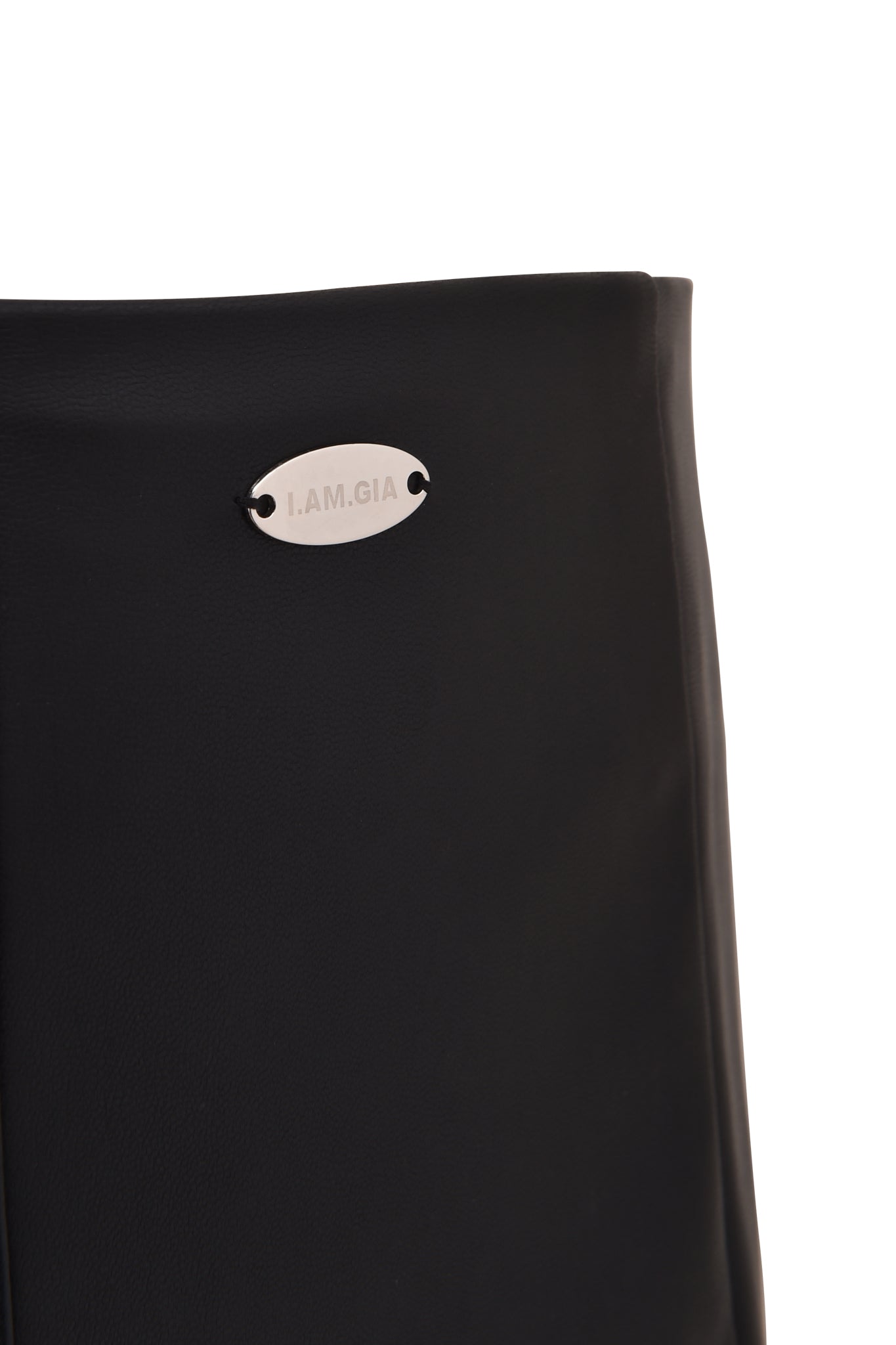 Close-up of the TEMPEST HOT SHORT - BLACK by I.AM.GIA, featuring black PU material and a small oval metallic “I.AM.GIA” label near the top left edge.