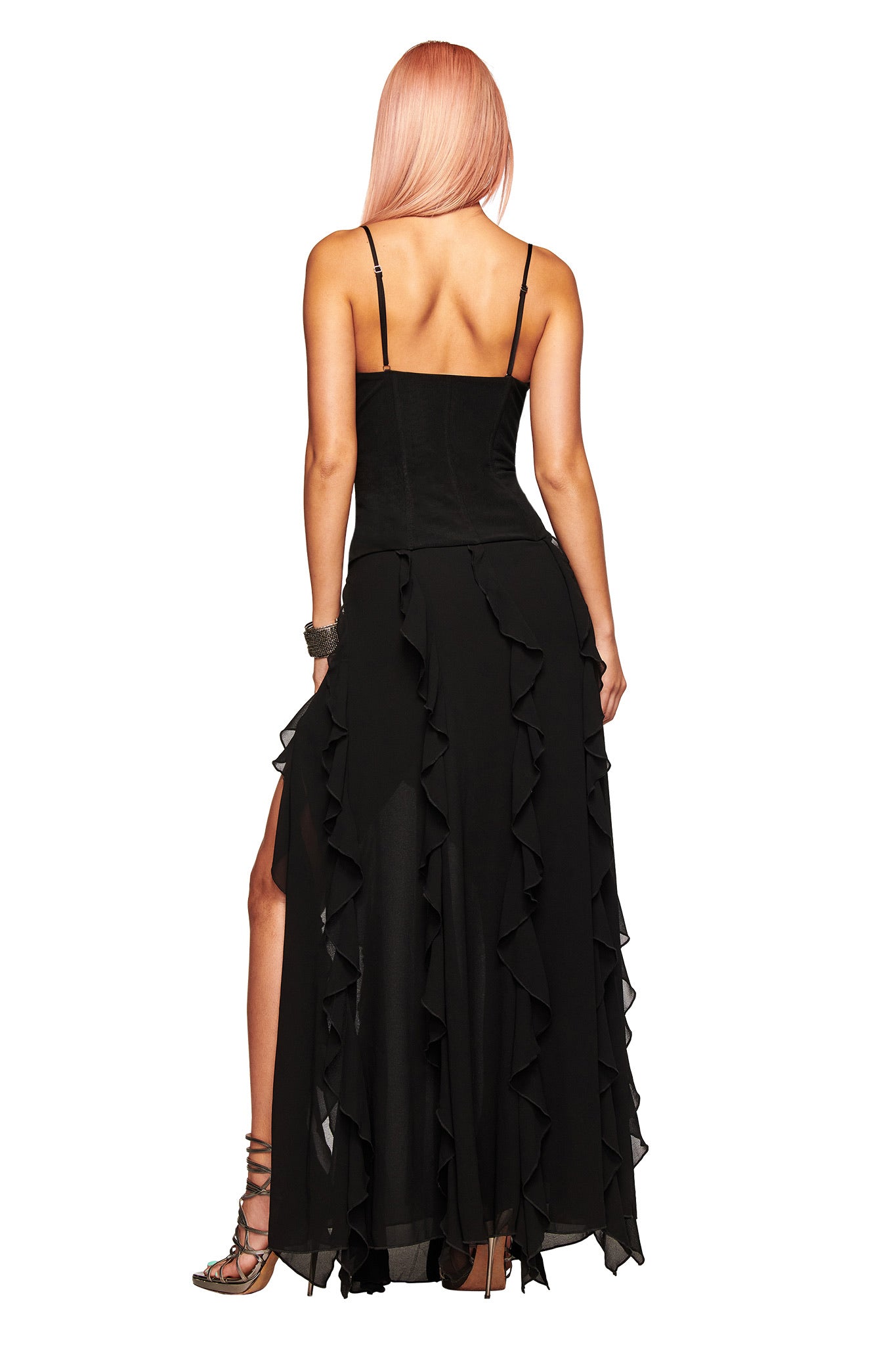 A woman with long pink hair, wearing the I.AM.GIA MARLETTE 2.0 Maxi Dress in black and ankle-strap sandals, stands facing away from the camera against a white background.