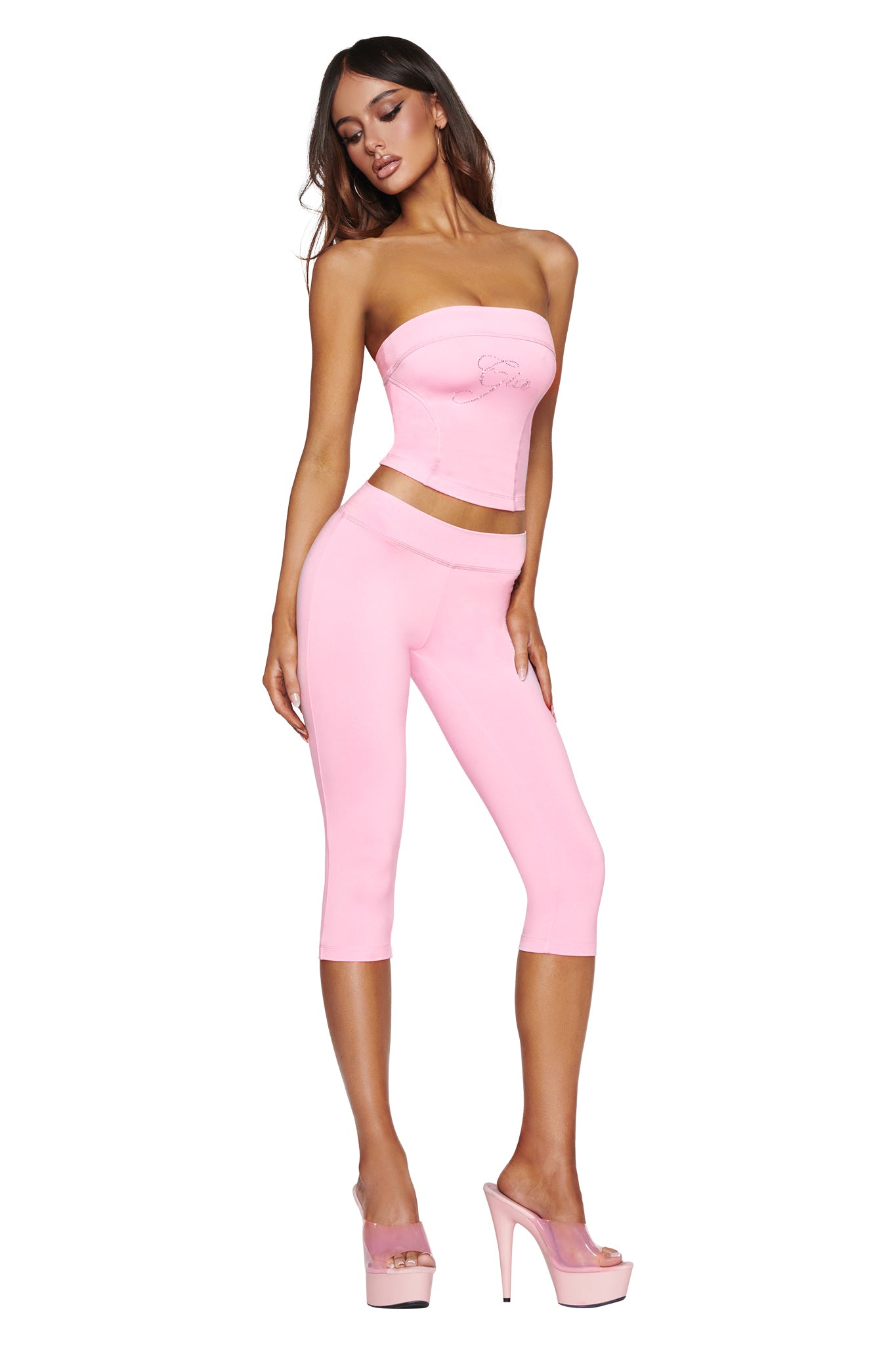 A woman poses in the I.AM.GIA BLARE DIAMONTE BOOB TUBE in baby pink with matching capri leggings and pink high heels.