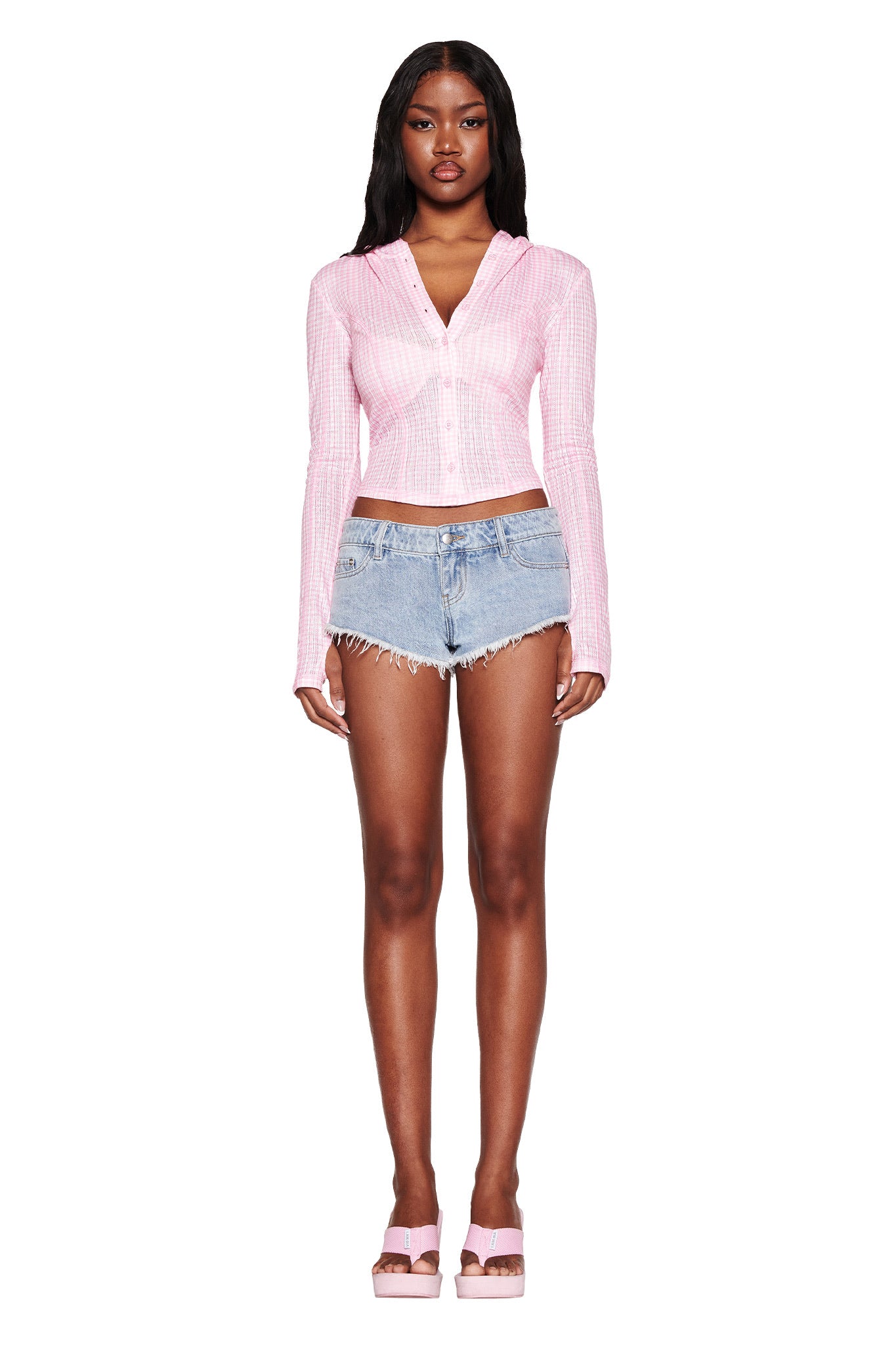A person with long dark hair stands against a white background wearing the I.AM.GIA MIA HOODIE in pink gingham and denim shorts, paired with pink platform sandals.