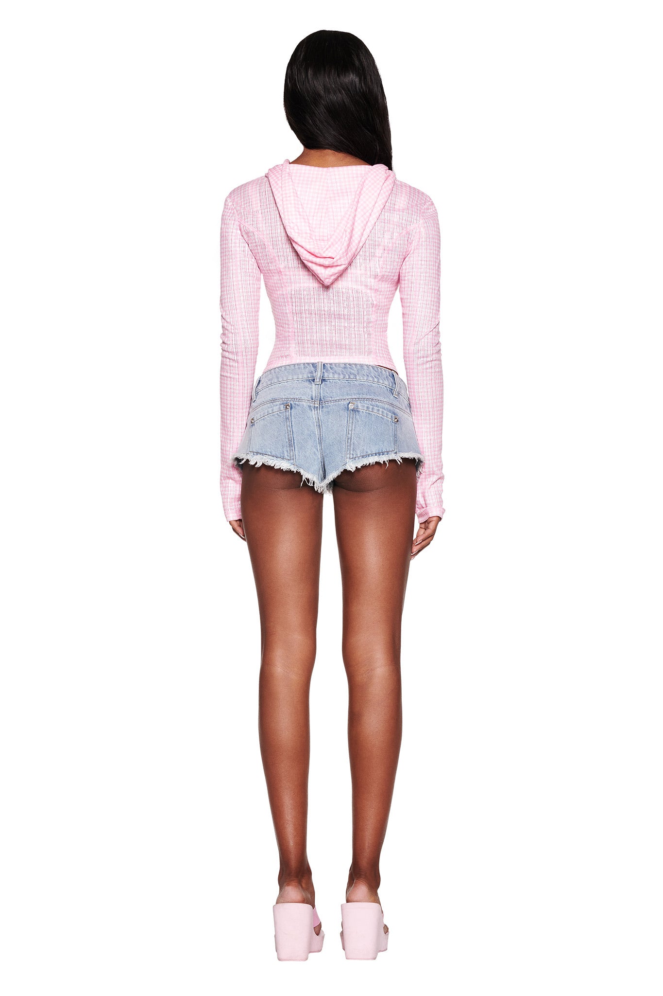 A person with long dark hair is seen in an I.AM.GIA MIA HOODIE - PINK GINGHAM and high-waisted denim shorts, paired perfectly with pink platform sandals against a plain white backdrop.