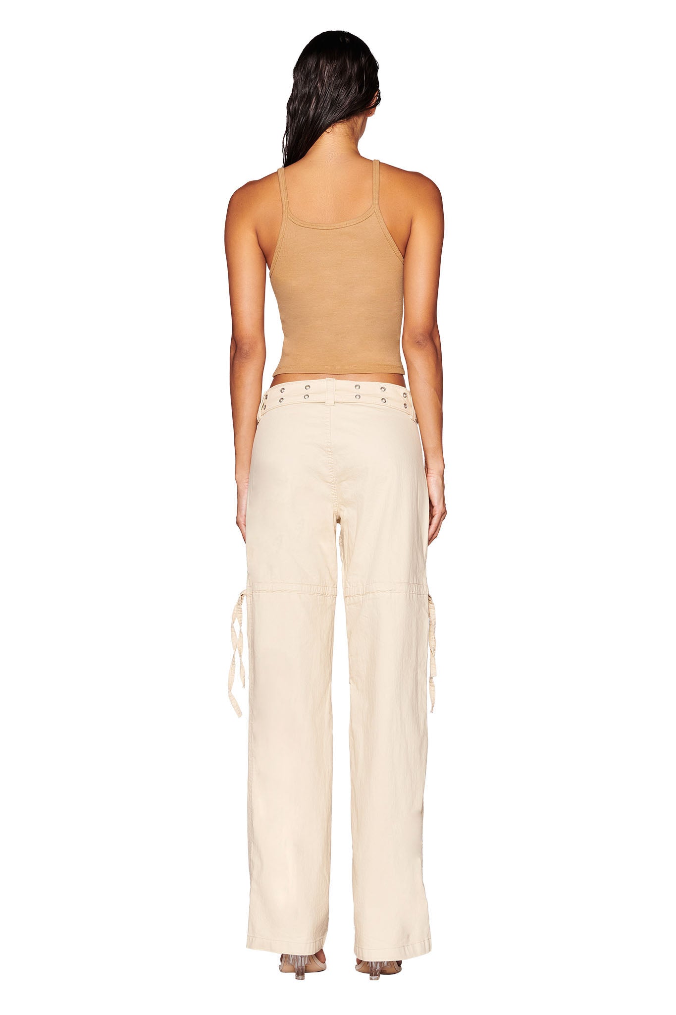 A person with long hair, viewed from behind, is wearing a tan sleeveless top and the I.AM.GIA NAIMA CARGO PANT in tan. The 100% cotton pants feature lace-up details at the waistband and side pockets. The person is standing against a plain white background.