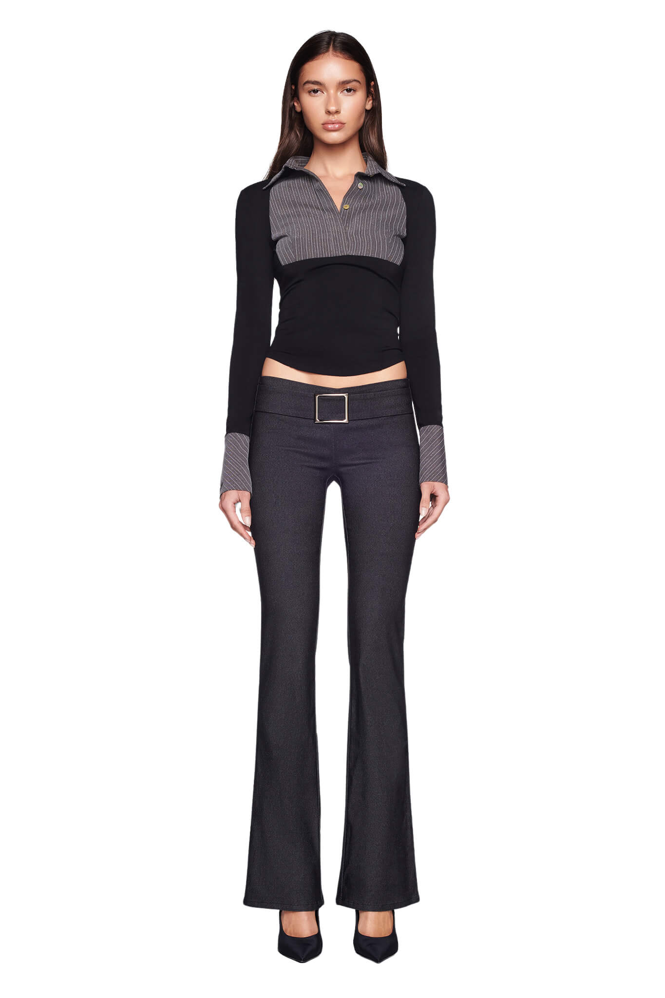 A woman stands against a white background, wearing the I.AM.GIA SHARAH TOP in black and grey, featuring a belted collar detail, and dark flared trousers. She has long brown hair and is dressed formally with black pointed-toe shoes.