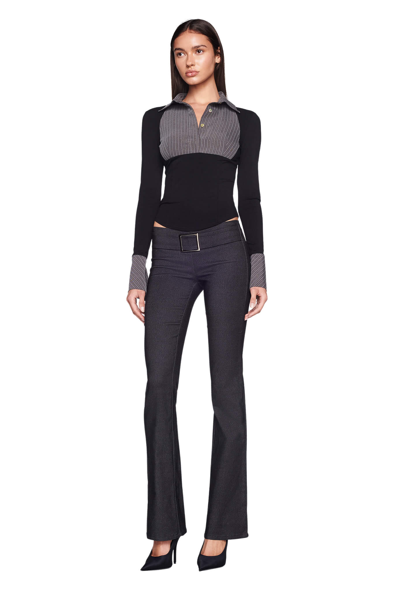 A woman stands against a white background wearing an I.AM.GIA black long-sleeve top with a striped collar and cuffs. She pairs this with the I.AM.GIA SHARAH PANT in grey, a belt, and black high-heeled shoes. Her arms are relaxed at her sides, and she has a neutral expression.