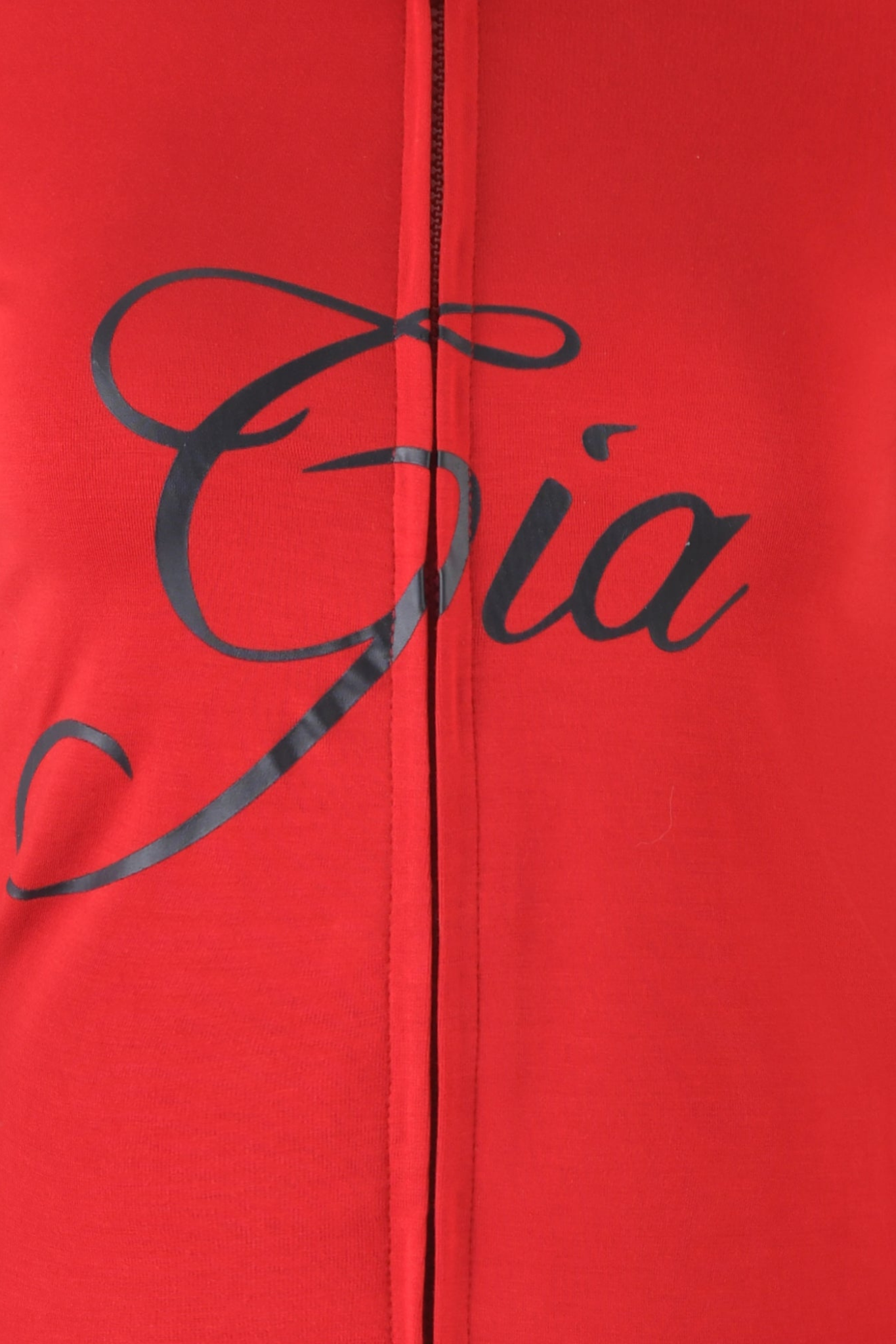 Close-up of red BLARE HOODIE by I.AM.GIA, featuring bamboo fabric with black script text reading “Gia.” A vertical seam runs through the center of the image.