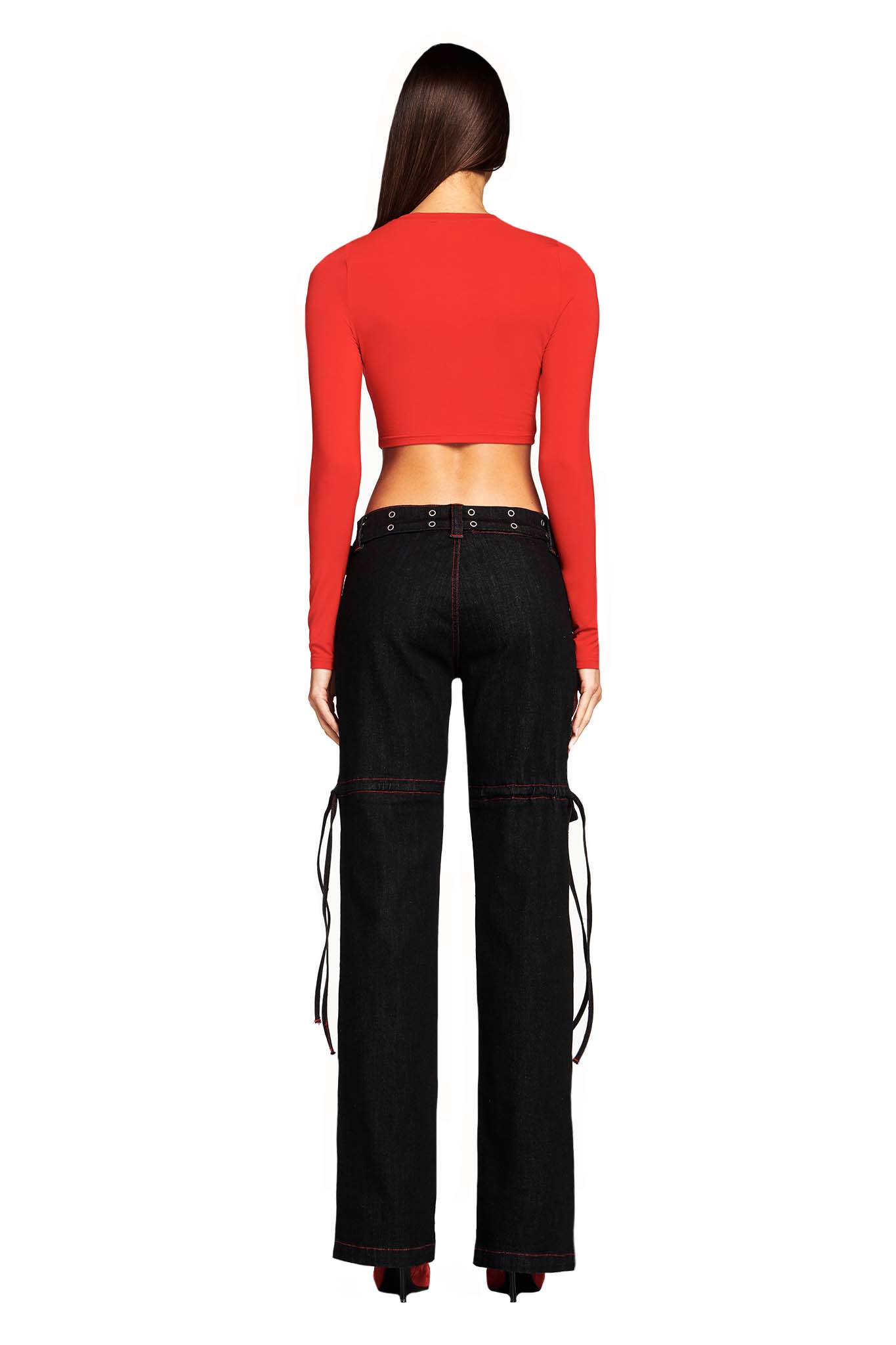 A person with long hair is shown from behind, wearing a fitted, long-sleeve red crop top and I.AM.GIA's Naima Cargo Pant in black with red side ties. The individual is standing against a plain white background.