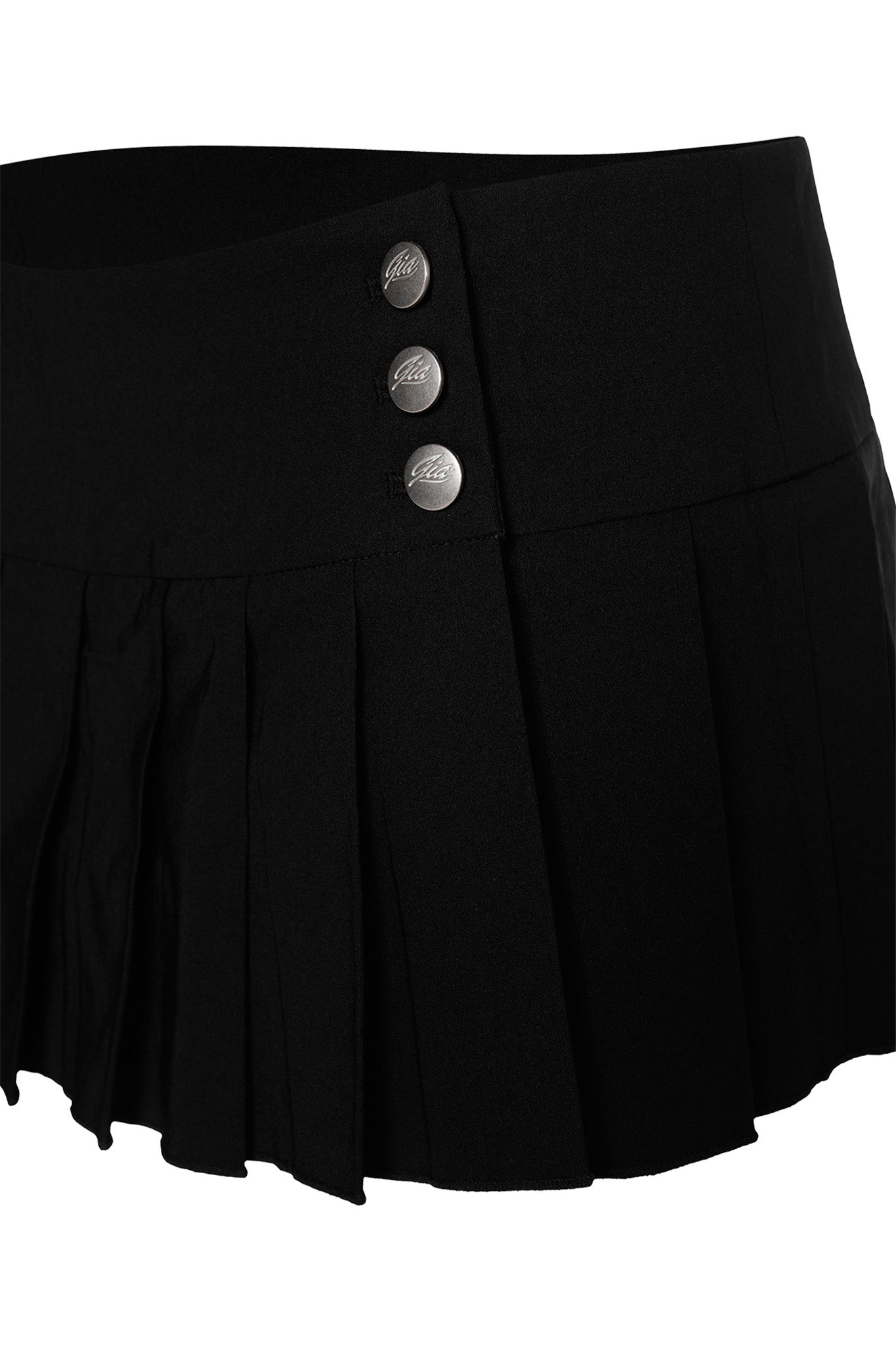The REMINI SKORT - BLACK by I.AM.GIA is a black pleated mini skirt featuring a thick waistband and three metallic buttons on the side. This skort has a simple yet stylish design, making it ideal for both casual and semi-formal outfits.