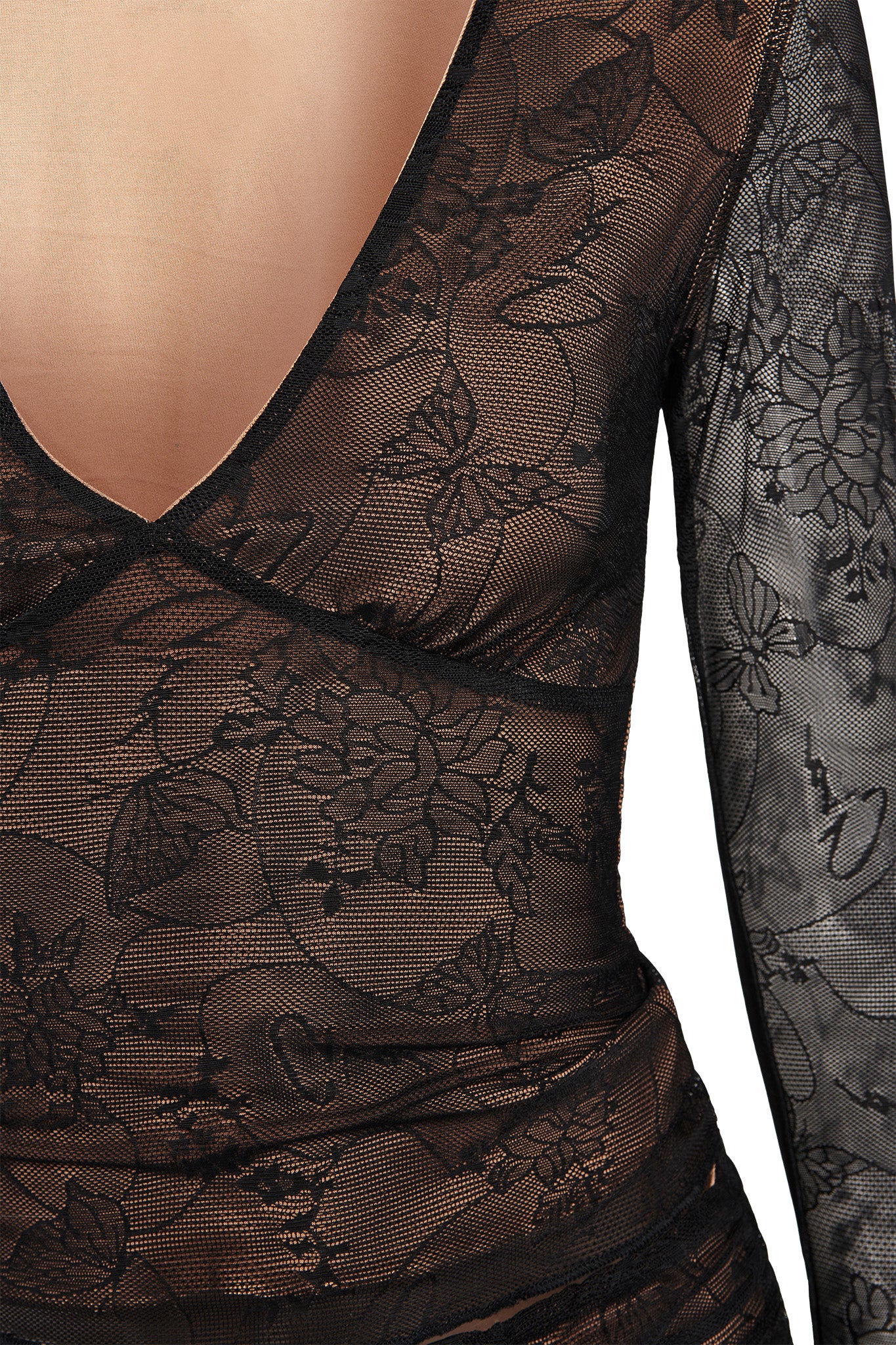 Close-up of a person's torso wearing the I.AM.GIA YVETTE TOP - BLACK : BUTTERFLY LACE. The sheer fabric showcases an intricate pattern of flowers and leaves, enhanced by delicate butterfly lace detailing. The deep V neckline and bodycon fit exude elegance, covering one arm to add a touch of sophistication to the ensemble.