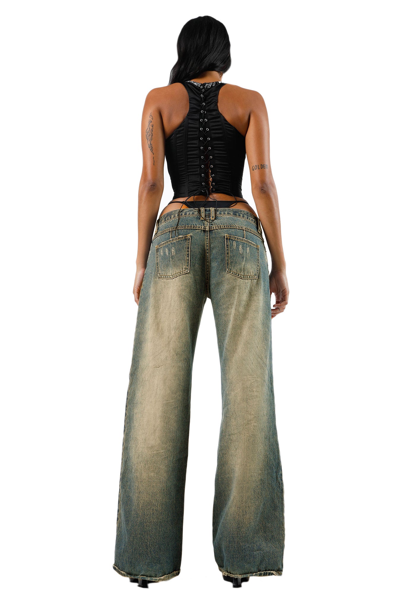 Rear view of a person wearing the SIOBHAN CORSET - BLACK by I.AM.GIA and a pair of wide-leg, faded blue jeans with visible back pockets. The person has long dark hair and stands against a white background.