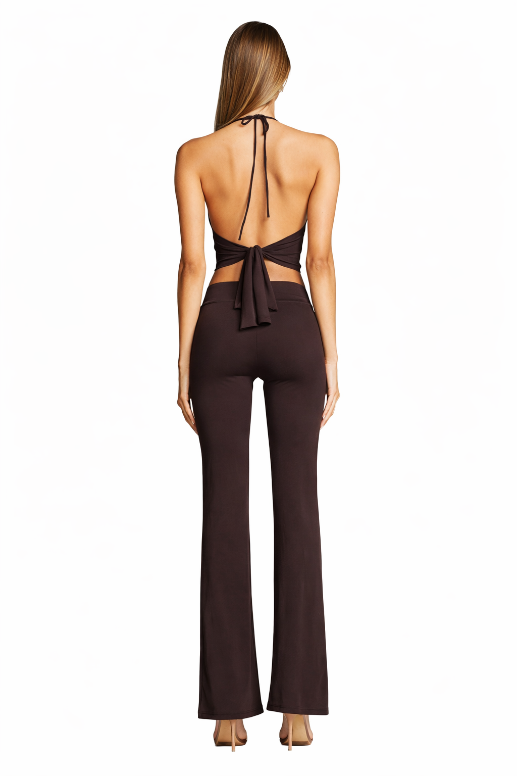 A woman faces away, wearing the I.AM.GIA SIOFRA TOP in brown with silver hardware and open back, styled with matching high-waisted flared pants and nude heels, set against a plain white background.