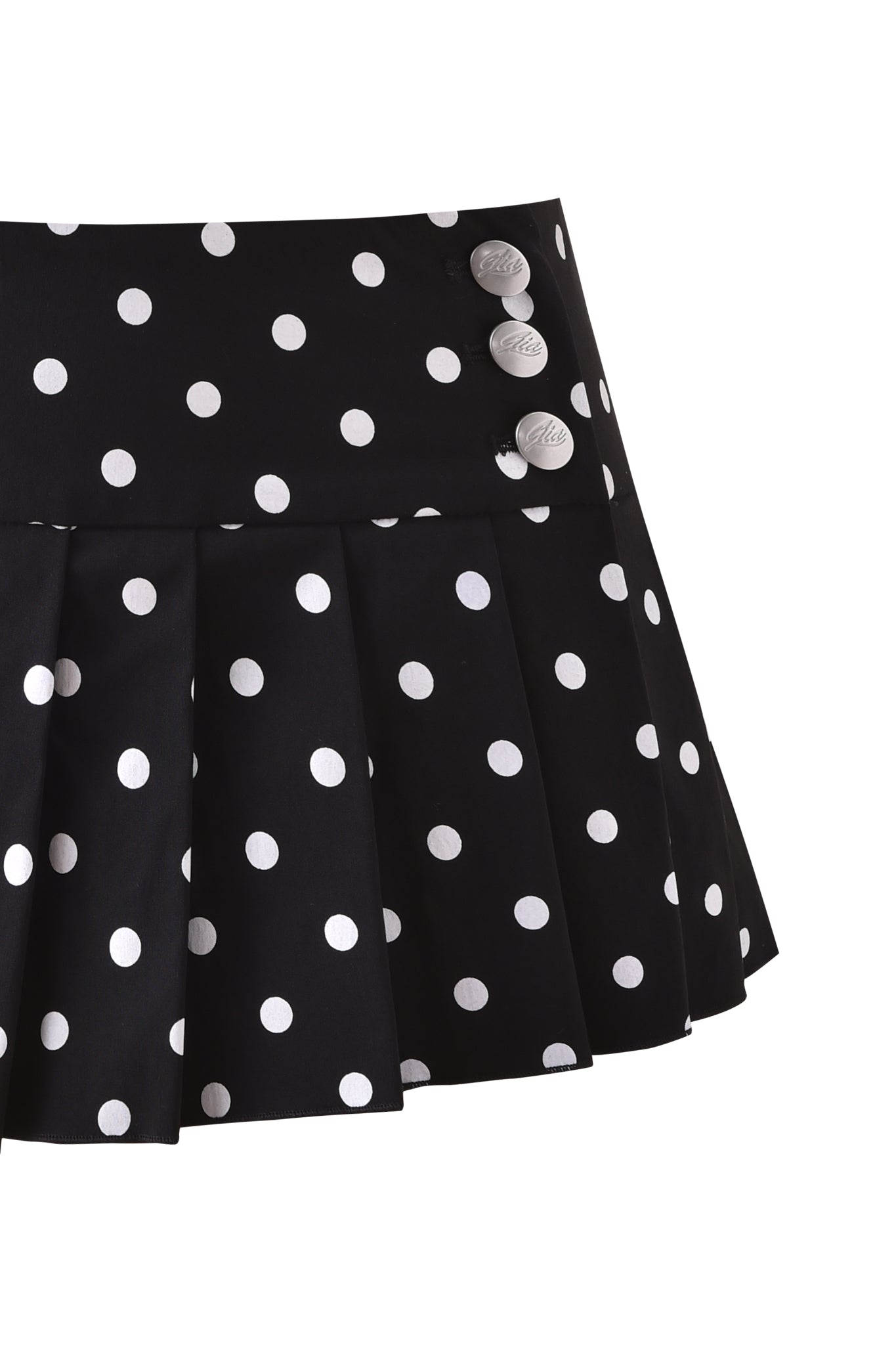 The REMINI SKORT - BLACK POLKADOT by I.AM.GIA is a black pleated micro mini skort with white polka dots and three white buttons on the waistband, shown against a white background.