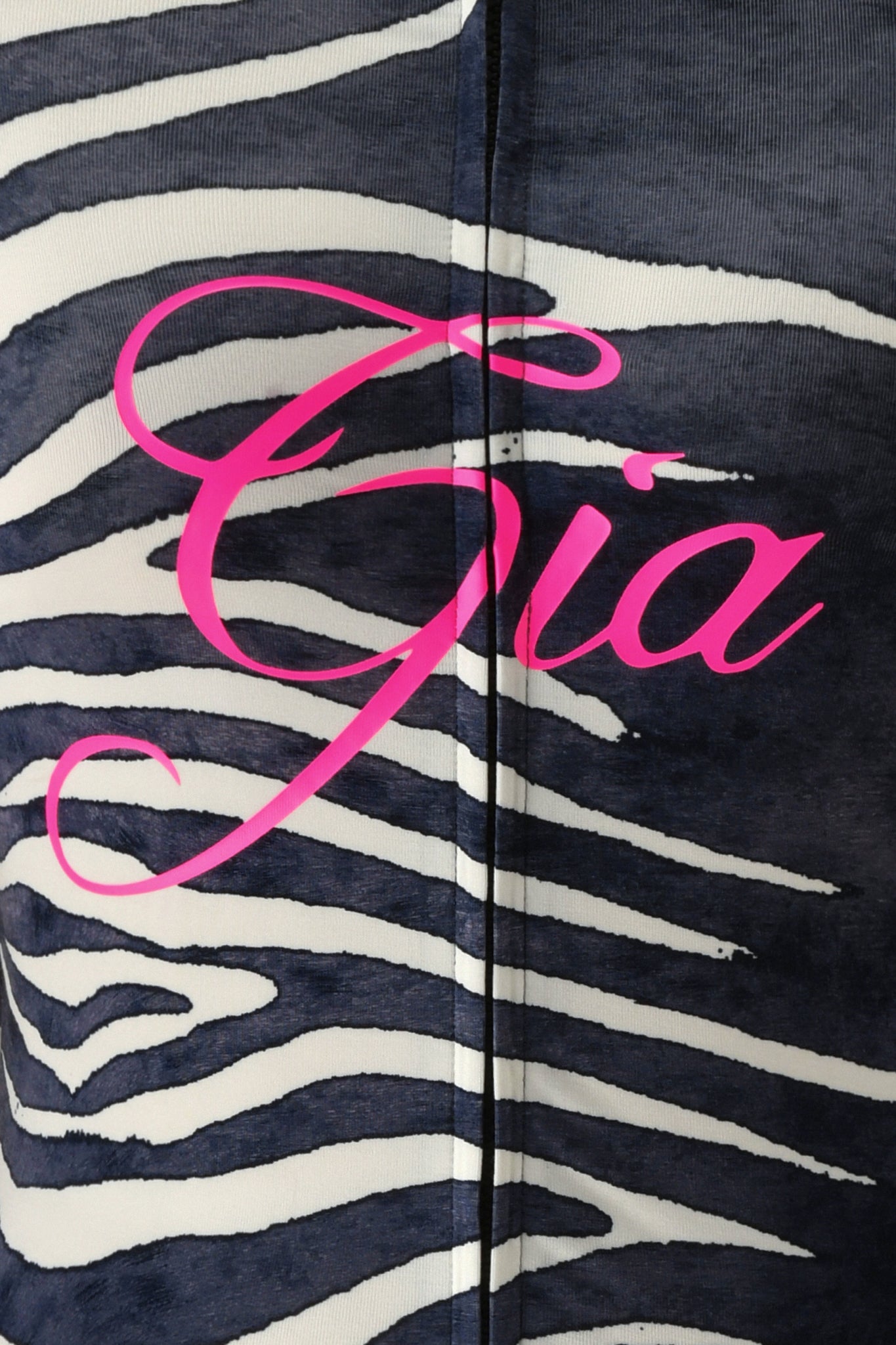 Close-up of the BLARE HOODIE - BLACK WILD SIDE from I.AM.GIA, showcasing its striking black and white zebra print fabric with the name “Gia” emblazoned in large, pink cursive letters across the center.