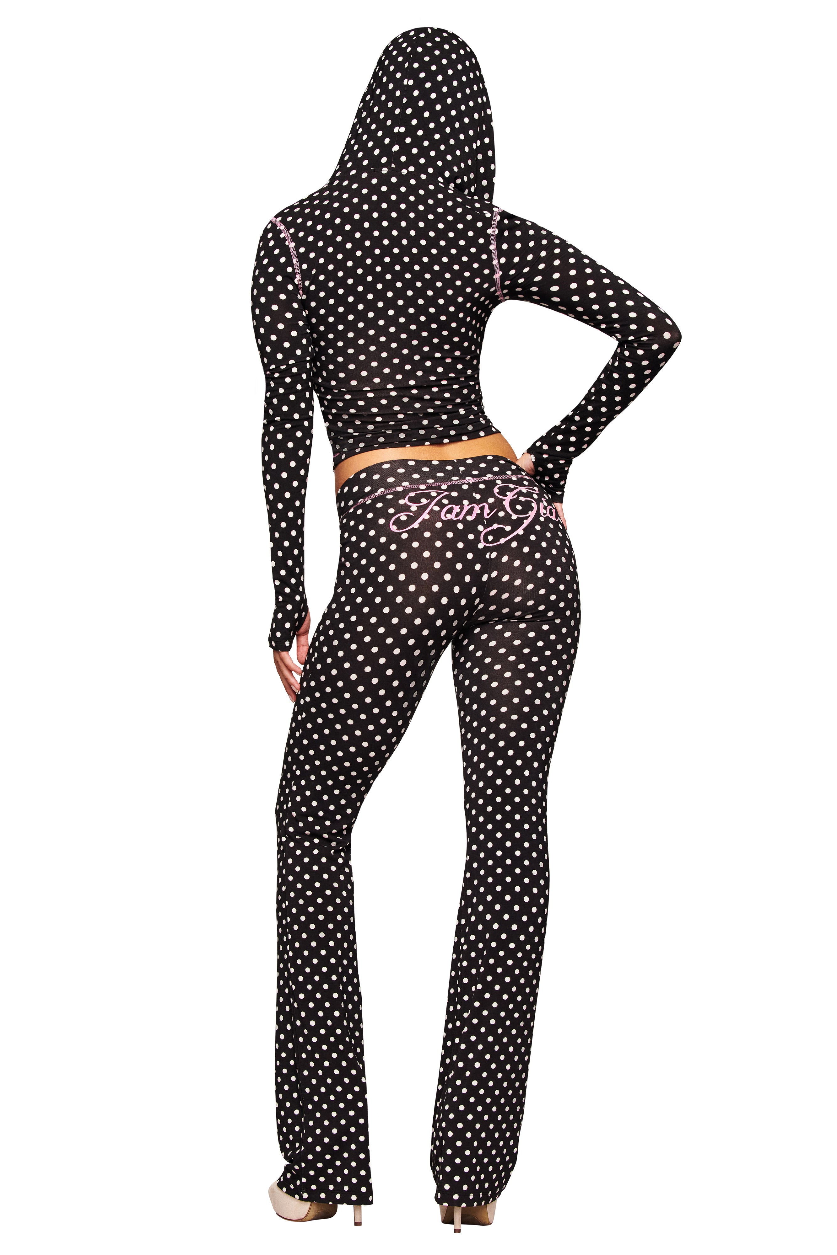 A person faces away, wearing the I.AM.GIA BLARE HOODIE - BLACK POLKA DOT with matching pants. The bodycon set features white polka dots, pink accents, and “Fancy Girl” in pink on the back of the pants; hood is up.