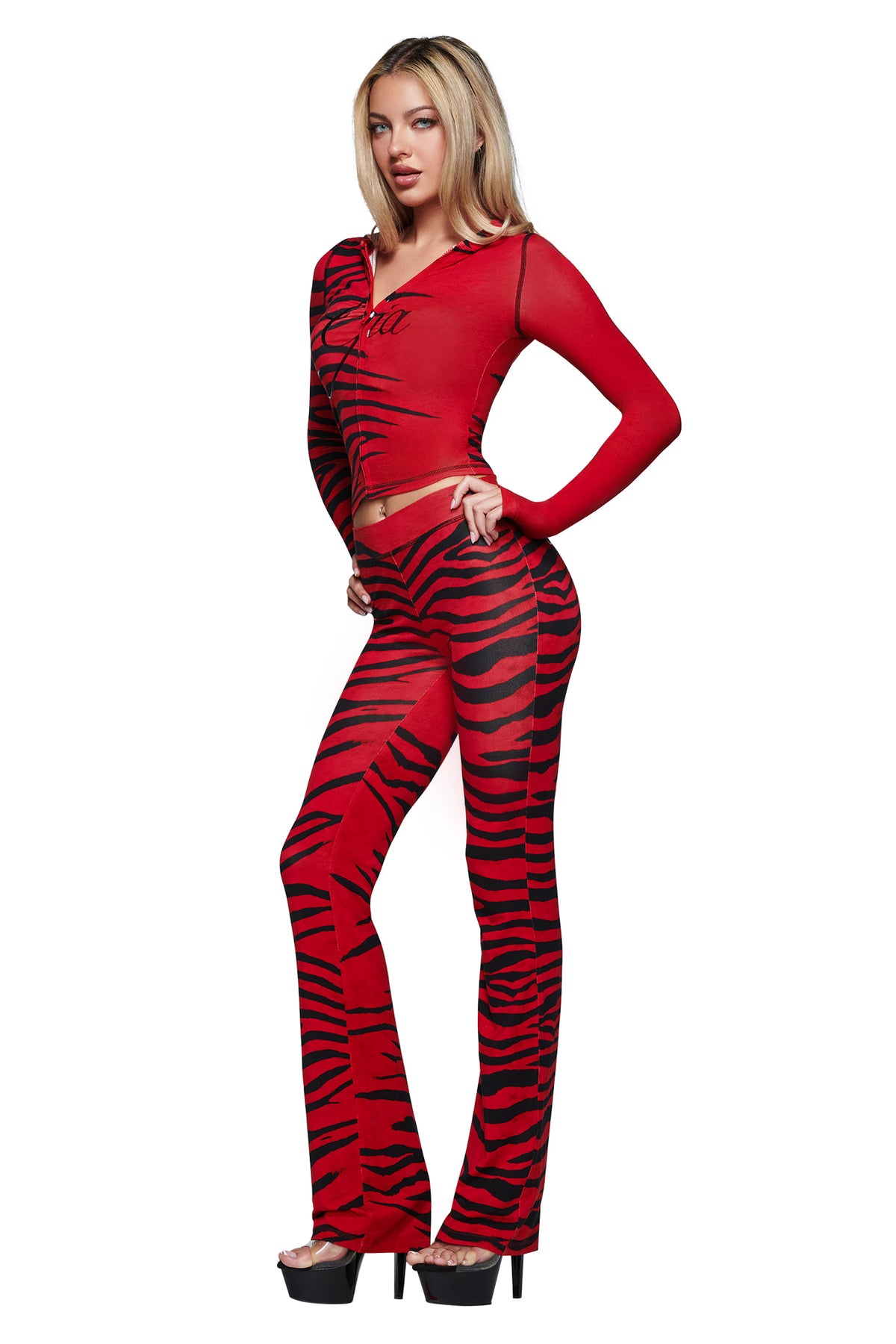 Wearing the BLARE HOODIE in Red Wild Side by I.AM.GIA, a woman strikes a pose in the bold zebra-print design styled with black platform heels.