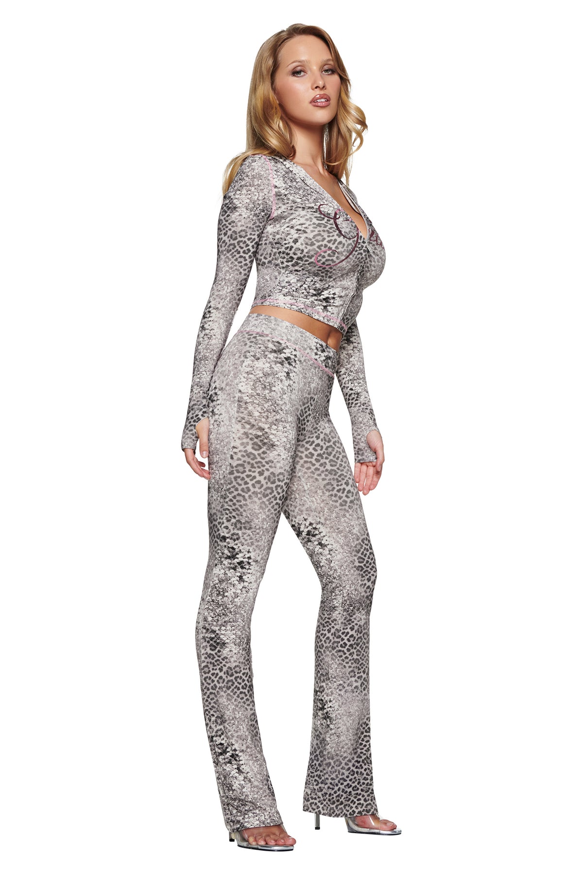 A woman wearing a BLARE HOODIE - SILVER LUXE LEOPARD cropped zip-up hoodie and matching high-waisted flared pants.