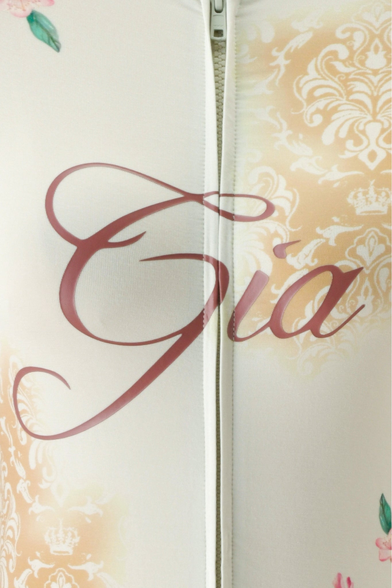 Close-up of the BLARE HOODIE - BLOSSOM by I.AM.GIA, showcasing a zipper detail, the brand’s name “Gia” in elegant script, and a soft pastel floral blossom print—perfectly capturing the charm of this bamboo hoodie.
