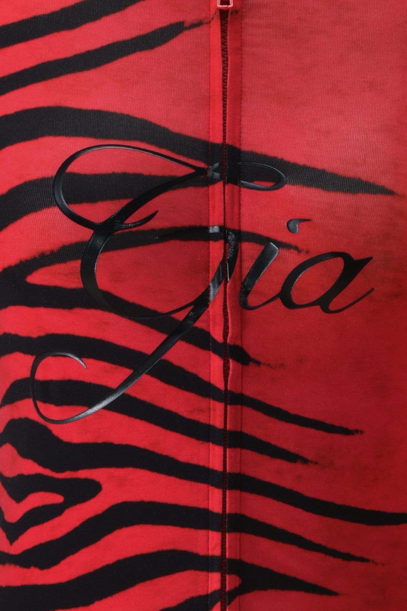 Close-up of the BLARE HOODIE by I.AM.GIA, featuring the signature Red Wild Side print—a bold red fabric adorned with black tiger stripes—crafted from soft bamboo material and finished with “Gia” elegantly scripted in black across the center.