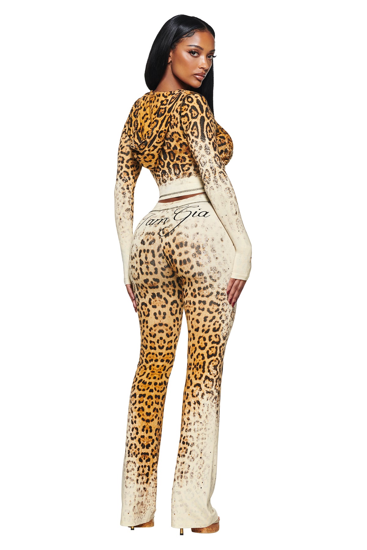 A person wearing a cropped BLARE HOODIE - CREAM FADED PANTHERA and matching fitted pants with script text on the back waistband.