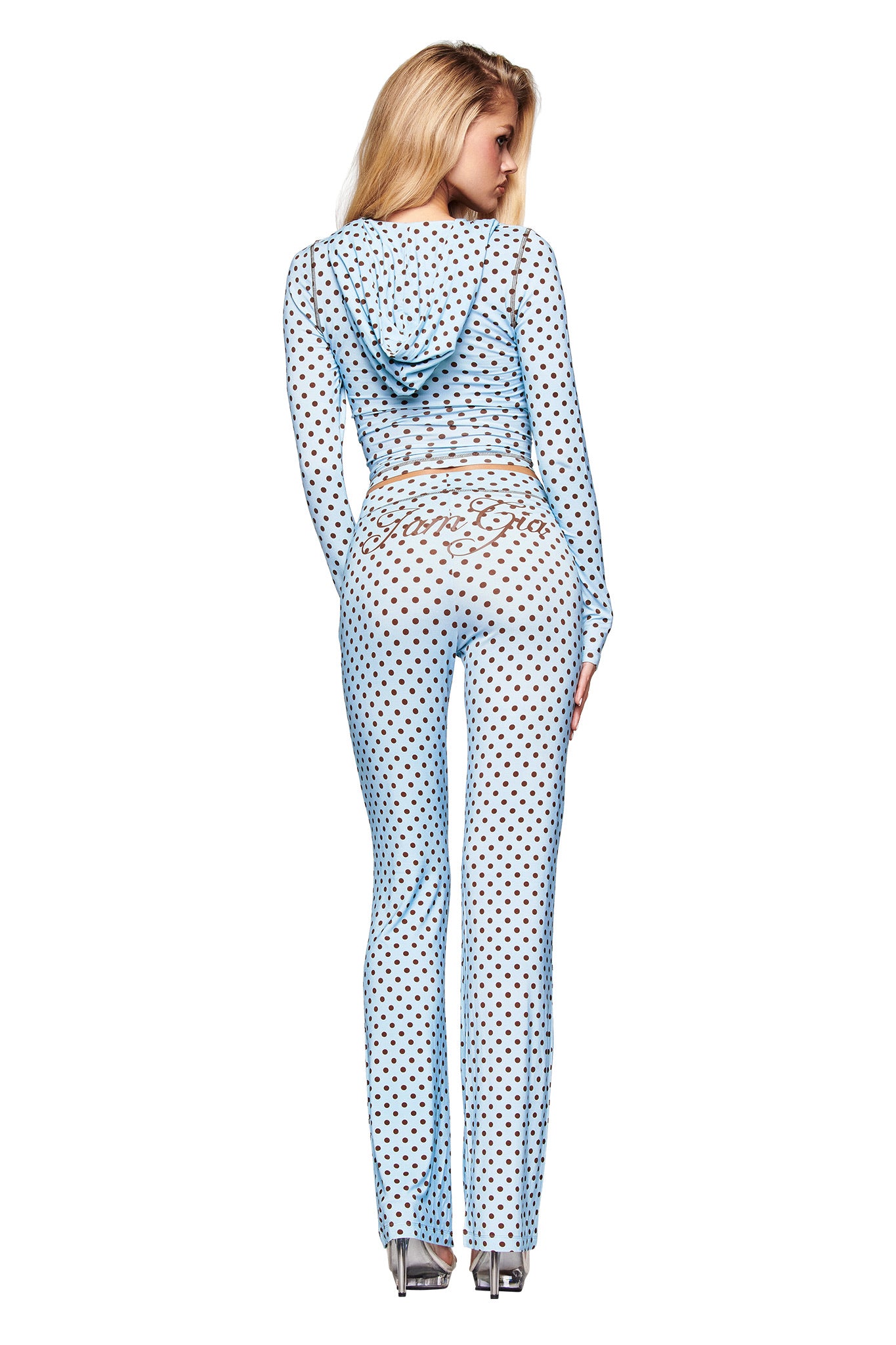 A woman with long blonde hair stands with her back to the camera against a white background, wearing the I.AM.GIA BLARE HOODIE in blue polka dot and matching pants.