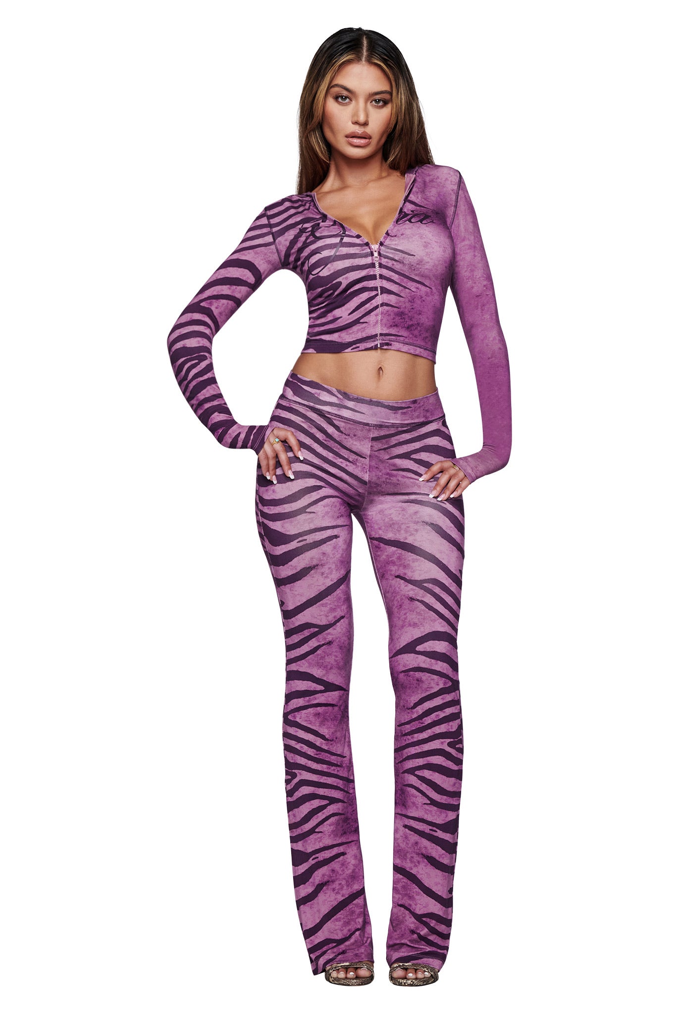 A woman faces forward wearing the I.AM.GIA BLARE HOODIE in Plum Wild Side, styled with high-waisted flared pants and high-heeled sandals.
