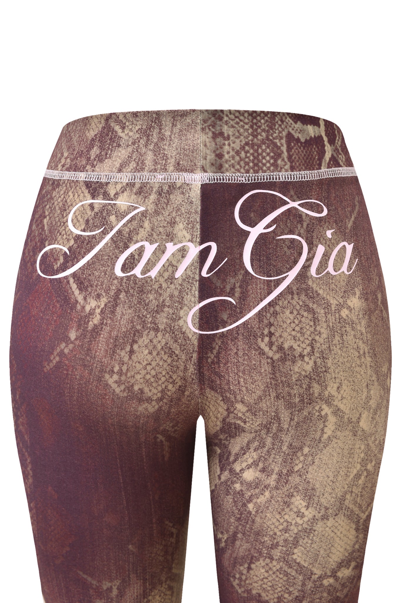 A close-up of the BLARE TRACKPANT - SNAKE by I.AM.GIA shows brown snake print leggings made from bamboo fabric, featuring "I.AM.GIA" in bold white script across the upper back.