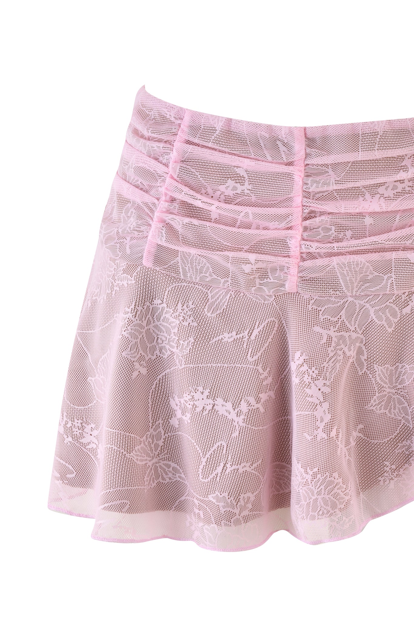 The YVETTE SKIRT - PINK by I.AM.GIA is a delicate lace piece in baby pink, featuring intricate floral patterns and gathered detailing at the waist. The sheer fabric reveals a subtle layer beneath, while the low-rise mini skirt flares slightly towards the hem for an elegant touch.