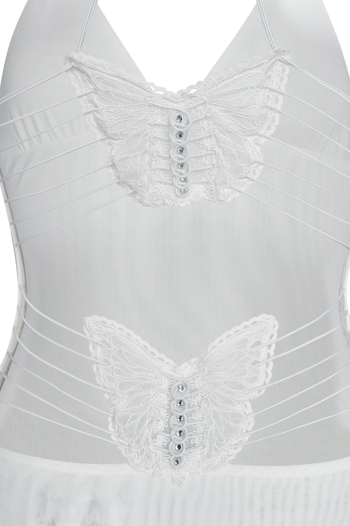 A close-up image of the ELLERY DRESS - WHITE by I.AM.GIA showcases its intricate lace butterfly appliqués. The appliqués are adorned with small white buttons in their centers, and several thin straps detail the sides, creating a delicate and elegant design.