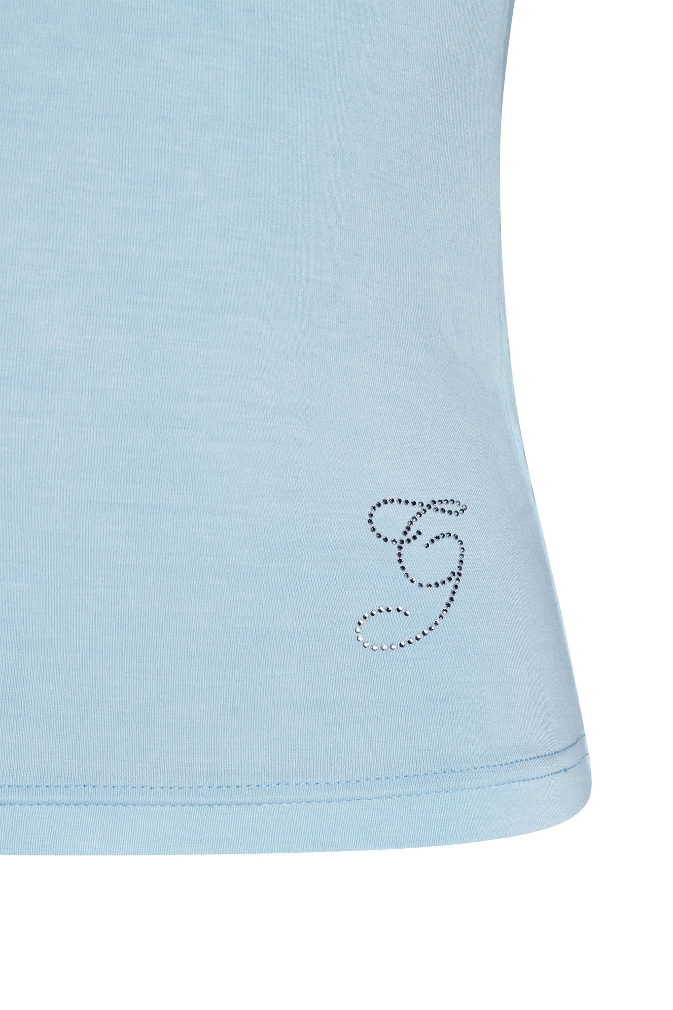 A close-up of the lower part of an I.AM.GIA ERIN TOP - BABY BLUE shirt. The shirt features a small, elegant "G" logo outlined in rhinestones near the bottom hem on the right side. The fabric appears soft and smooth.