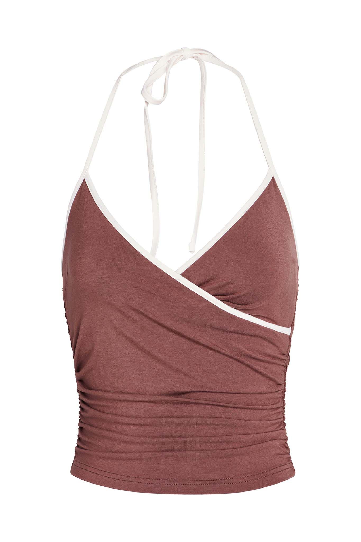 The JANNIS TANK - BROWN : CHOCOLATE by I.AM.GIA is a stylish halter-neck crop top with white straps and trim. Made from bamboo fabrication, this top features a wrap-style front and side ruching for a fitted look. The V-shaped neckline highlights the halter design that ties at the back of the neck.