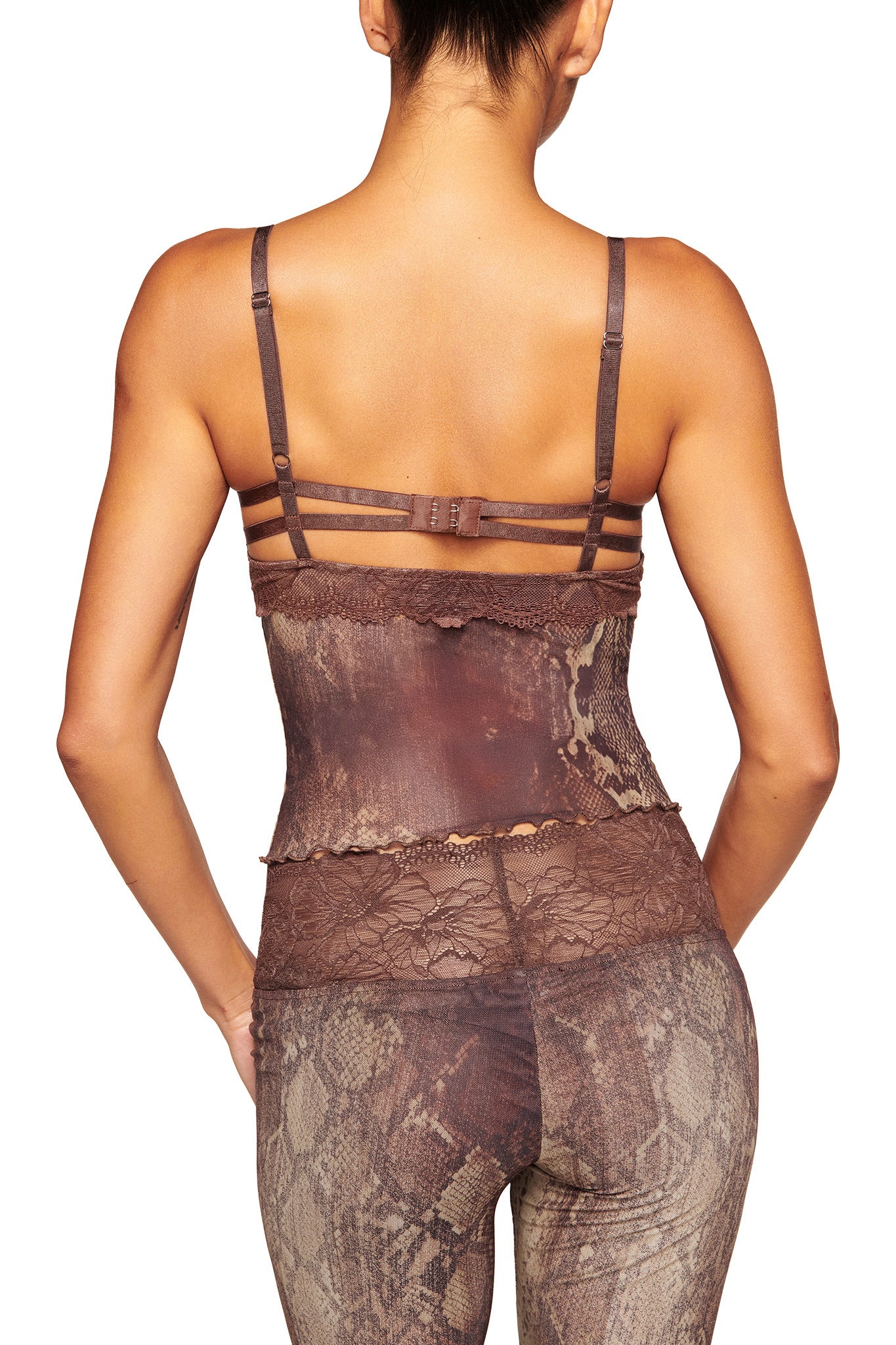 A woman is seen from behind in the I.AM.GIA SILO PANT - SNAKE, featuring a bold snake print with matching brown mesh camisole and adjustable straps. Her hair is tied up to highlight the striking patterned outfit.