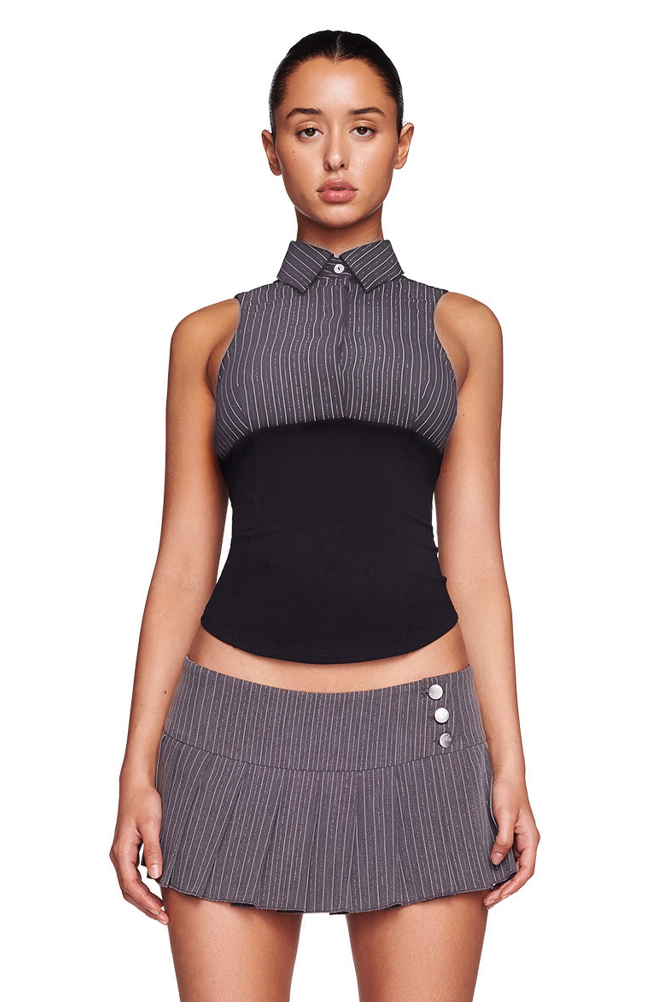 A person stands facing forward wearing the I.AM.GIA SHARAH TANK in black and gray, a sleeveless collared top with gray pinstripes and a black midsection, paired with a matching gray pinstripe skirt that has buttons on the upper right side. The background is plain white.