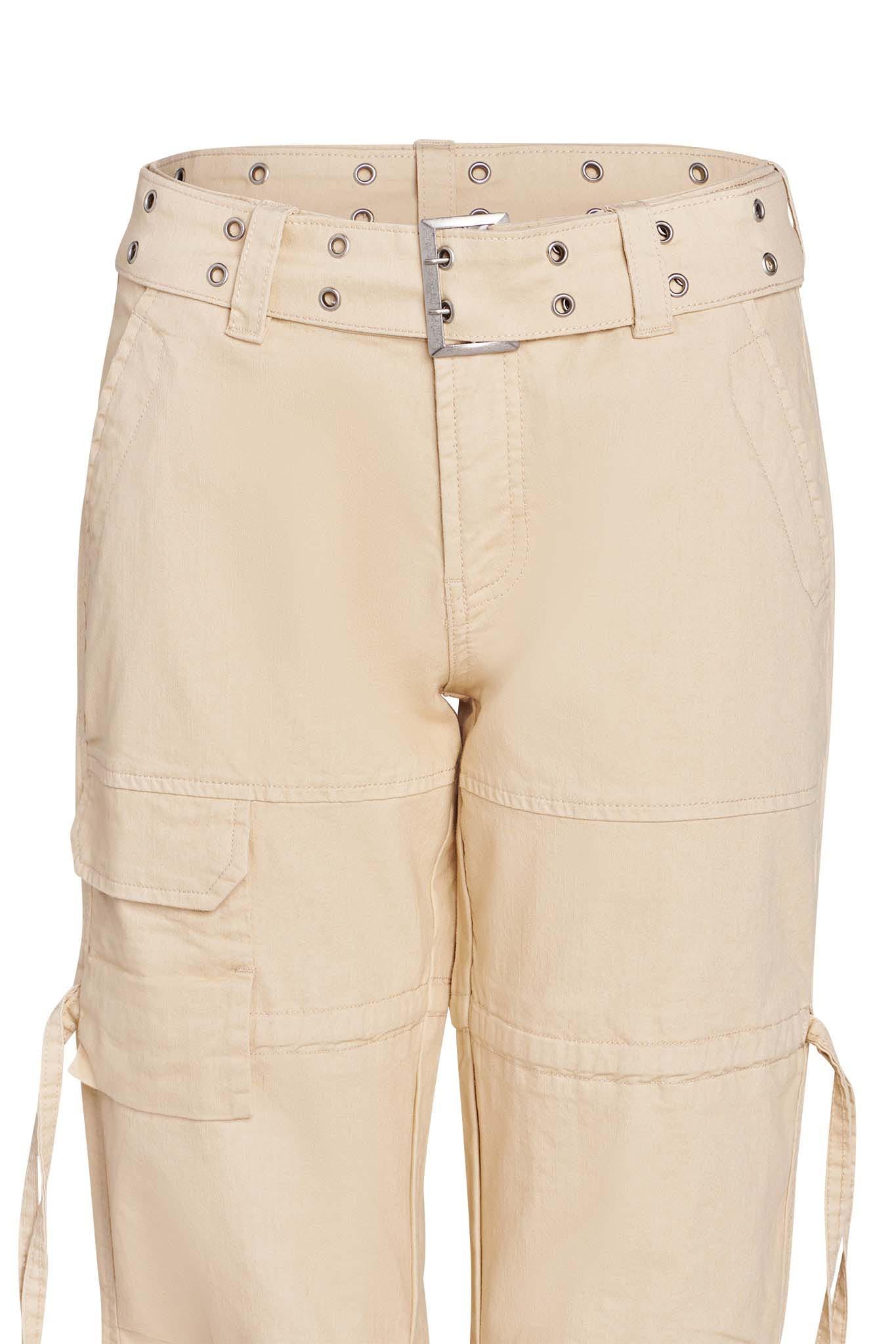 Close-up image of tan NAIMA CARGO PANT by I.AM.GIA featuring multiple pockets, belt loops, and an attached belt with metallic grommets. The pants present a casual, utilitarian style with stitching details. The fabric appears lightweight and suitable for everyday wear.