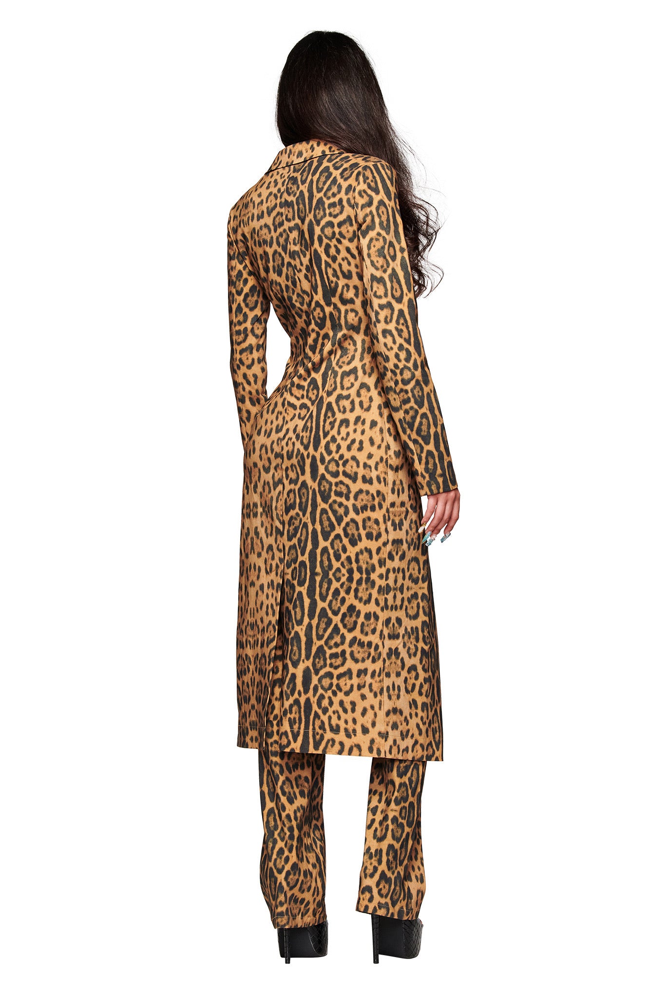 A person with long dark hair faces away, wearing the UMA COAT - PANTHERA by I.AM.GIA and matching pants in an animal print, paired with black platform shoes against a plain white background.