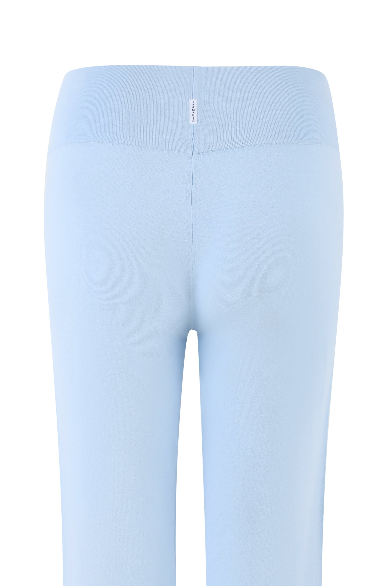 The image features the back view of the AUDRINA PANT - BLUE in Powder Blue from I.AM.GIA. These low-rise knit flare pants boast a seamless waistband crafted from smooth, soft fabric. Vertical stitching runs down the center of the back, and a small tag is attached to the tall rib waistband.