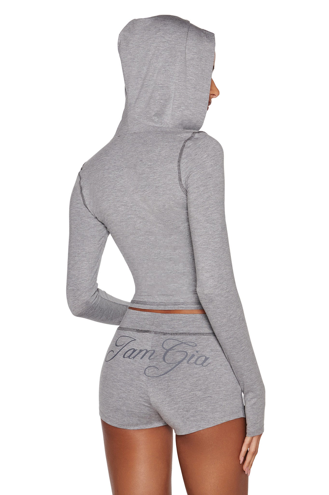 A woman is shown from the back wearing a light gray, long-sleeve hooded crop top and matching I.AM.GIA BLARE JERSEY SHORT in heather grey with "Iam Gia" printed on the back.