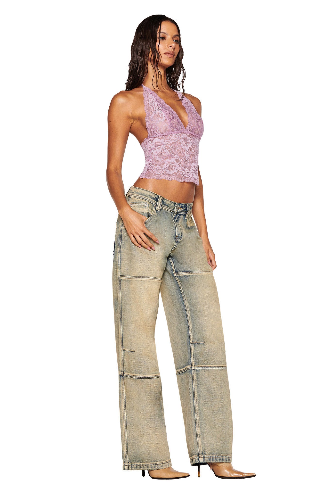 A person with long hair wears the GEM HALTER TOP by I.AM.GIA in lilac and baggy light-wash jeans, standing against a white background. They are wearing brown pointed-toe shoes.
