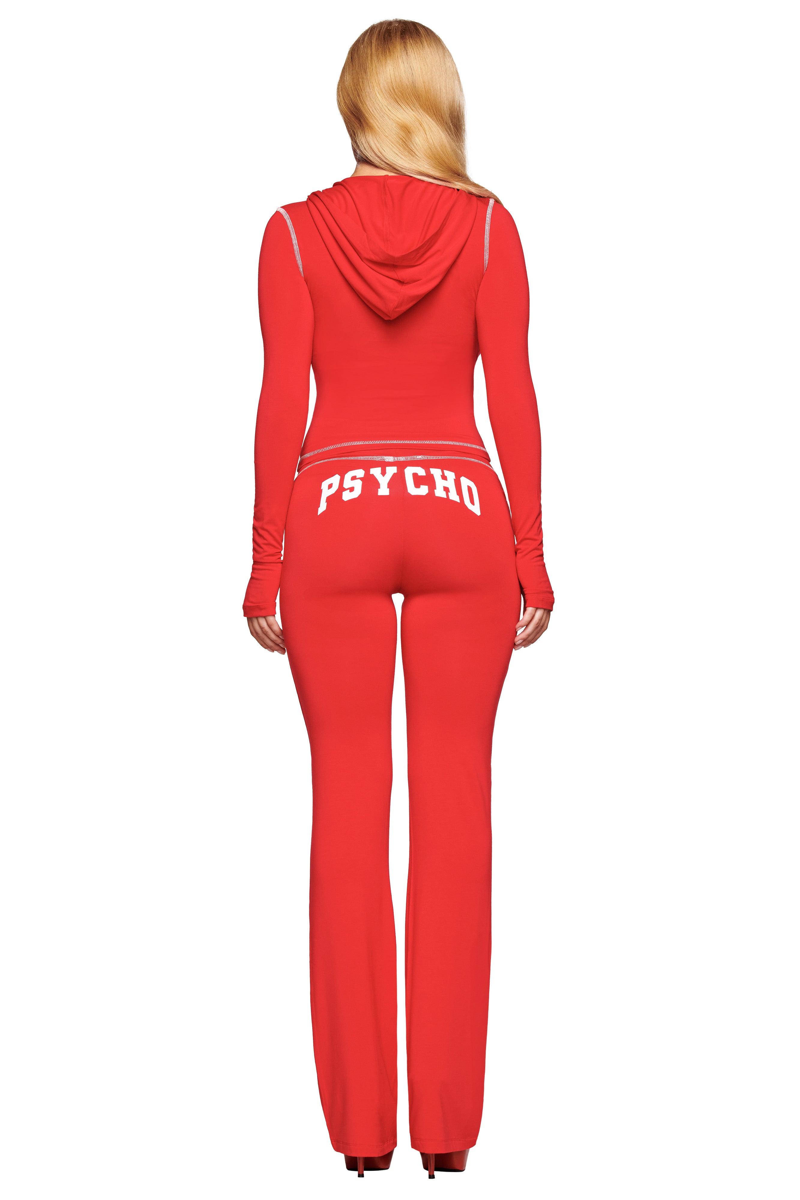 A woman with long blonde hair, seen from the back, wears I.AM.GIA’s BLARE TRACKPANT - RED : PSYCHO : SALSA, featuring “PSYCHO” in bold white letters across the back.