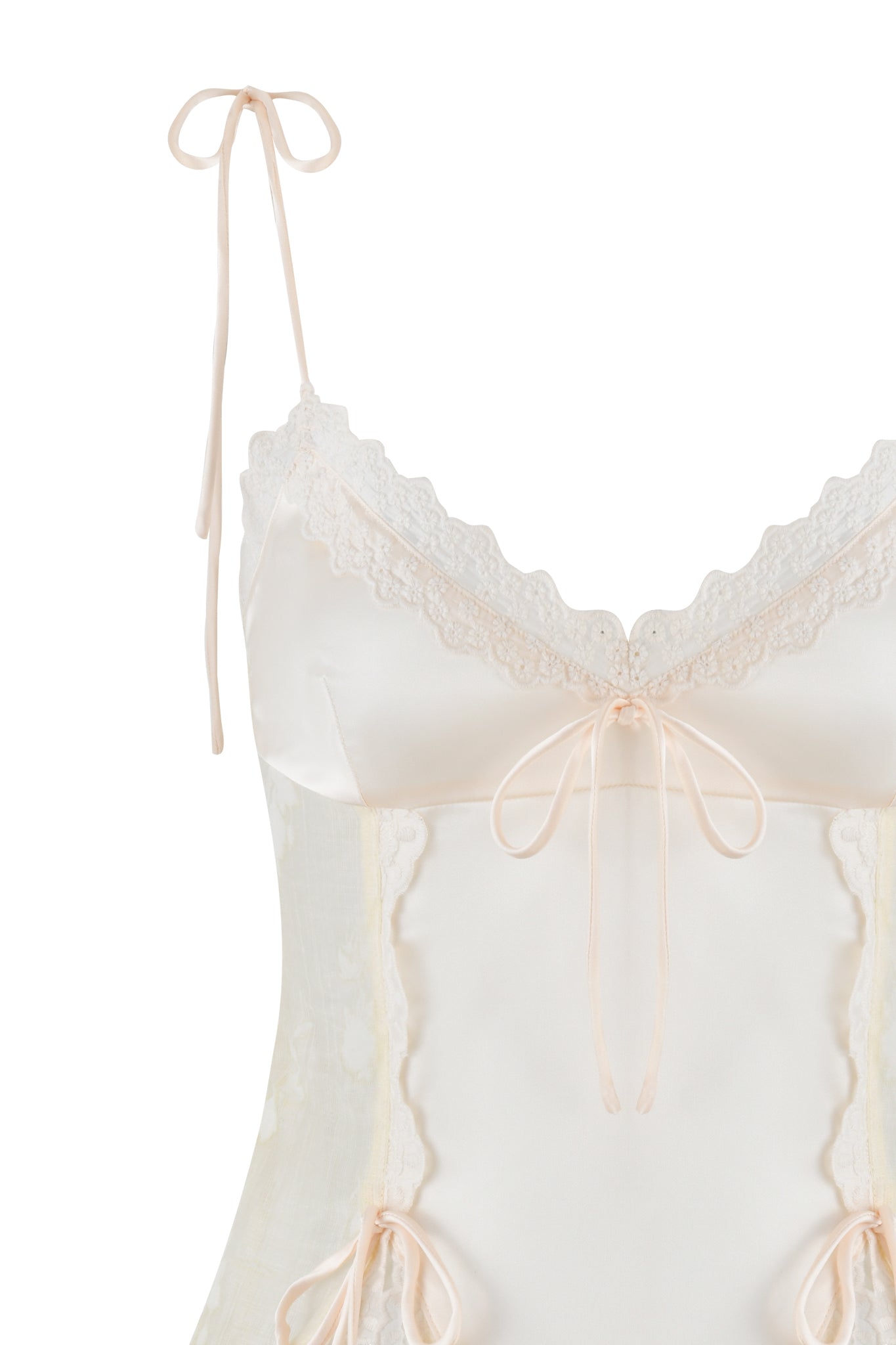 A close-up of the delicate MEADOW TOP - WHITE: FLORAL DELIGHT by I.AM.GIA, featuring luxurious stretch satin with lace trim, thin shoulder straps tied into bows, and small ribbon bows along the neckline and waist for a feminine and elegant look against a white background.