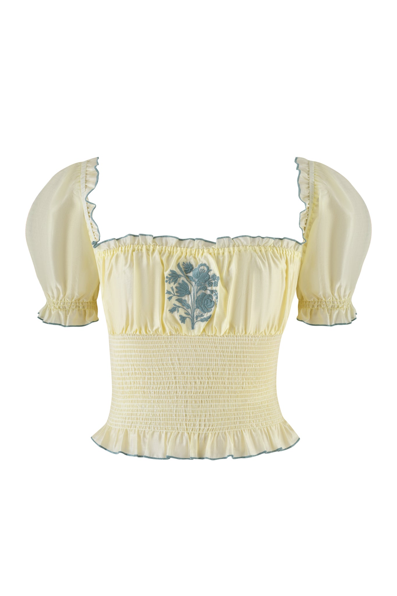 The I.AM.GIA CLOVER TOP - YELLOW is a pale yellow off-the-shoulder blouse with puff sleeves, a smocked bodice, green floral embroidery on the chest, and ruffled trim on the neckline and hem.