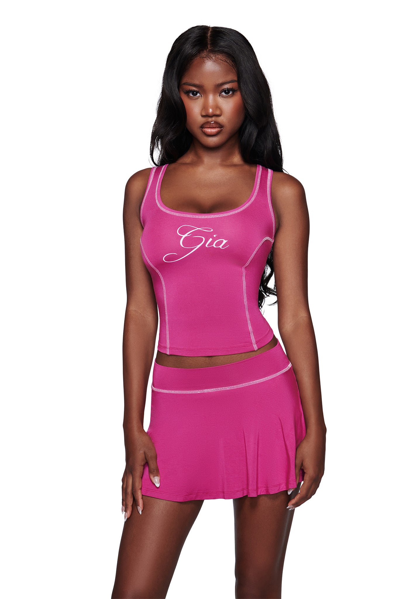 A woman with long dark hair wears the I.AM.GIA BLARE TANK in raspberry with a matching bodycon skirt, standing against a plain white background.