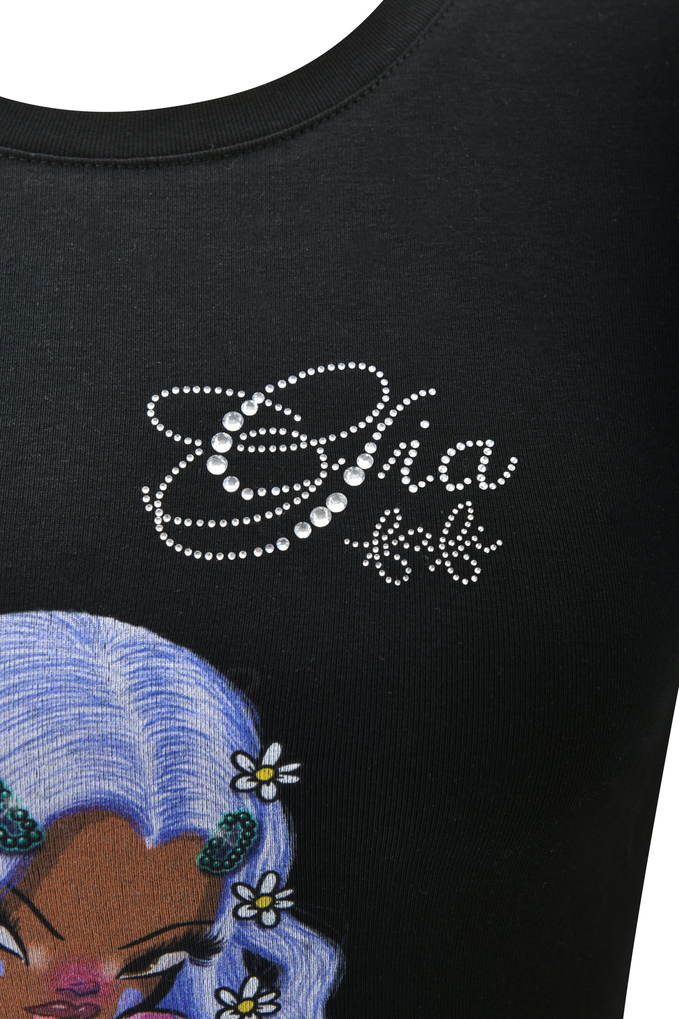 Close-up of the I.AM.GIA FAFI T-SHIRT in black, featuring diamanté "Gia bb" text above a graphic of a person with long, wavy, pastel purple hair adorned with small white flowers.