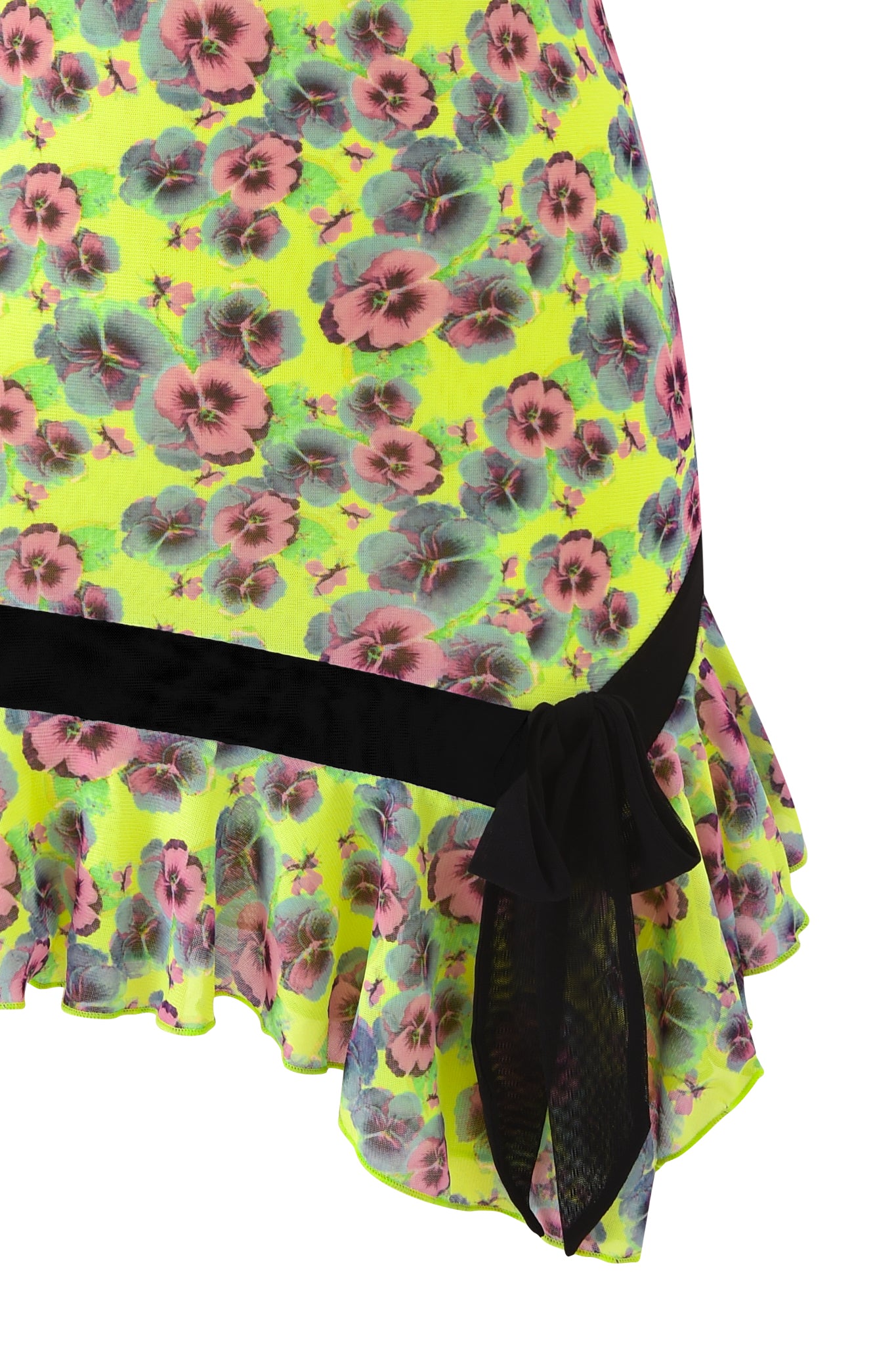 Close-up of the SUZIE MESH AND LACE MINI DRESS - SASSY PANSY by I.AM.GIA, showcasing yellow fabric with a vibrant pink and green floral pattern, black ribbon and bow accent, and a ruffled hem.