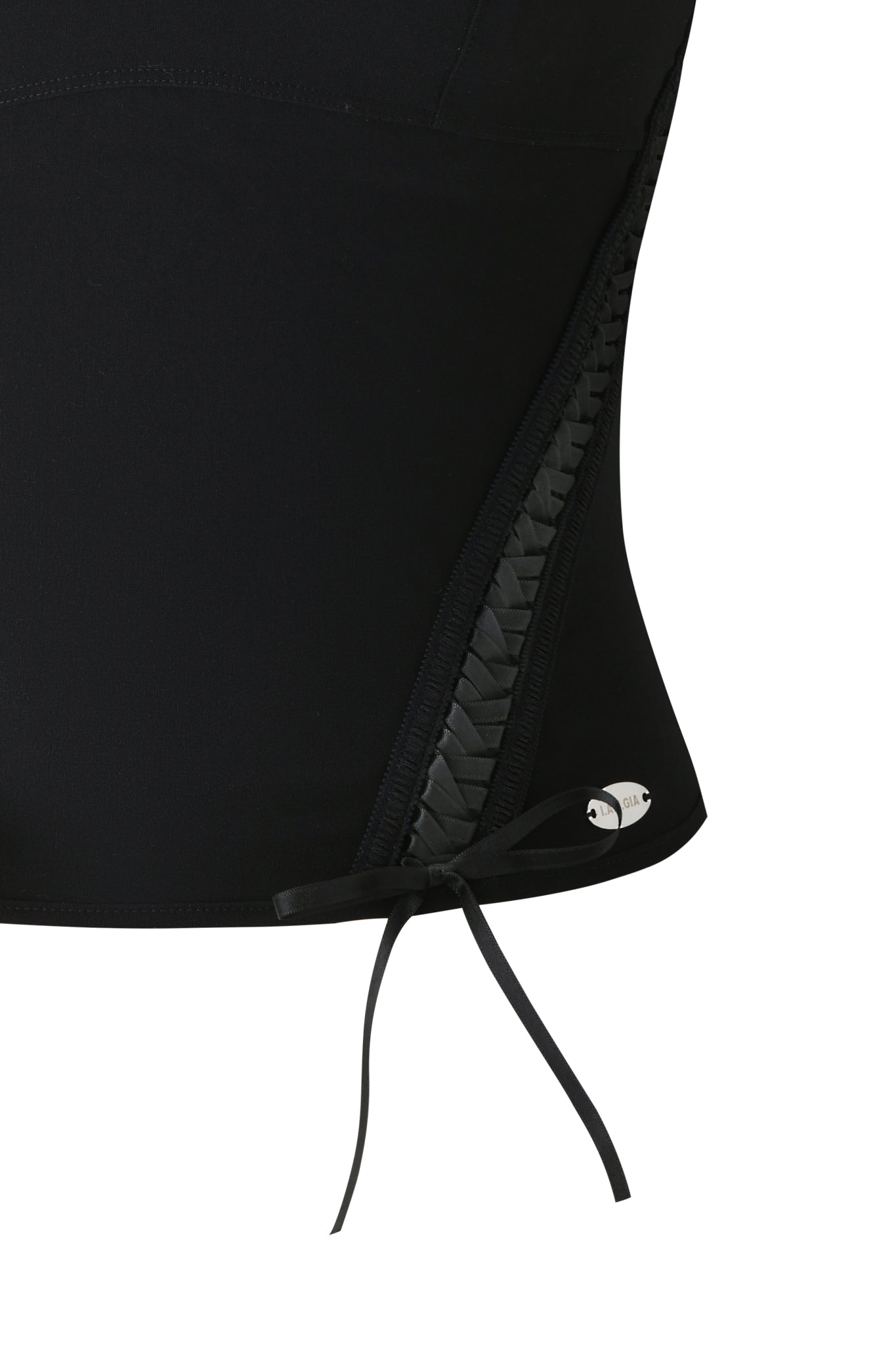 Close-up of the I.AM.GIA SAMIRA BUSTIER in black, showcasing a diagonal stretch woven panel, a silver fish-shaped emblem, and a thin black ribbon bow near the bottom edge.