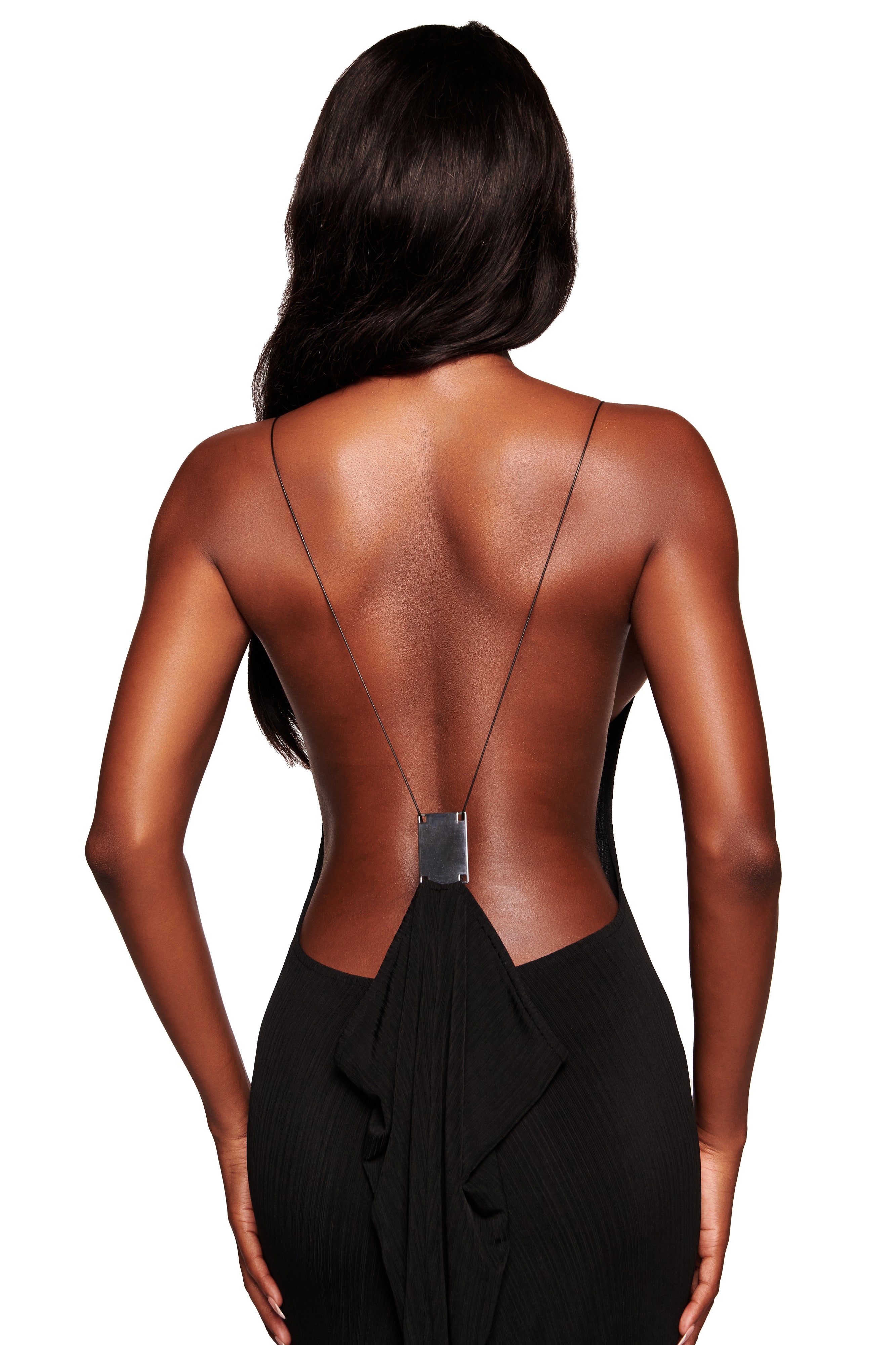 A woman with long dark hair is seen from the back wearing the I.AM.GIA SIMONE MAXI DRESS in black, featuring thin straps and a draped detail at the lower back, against a white background.