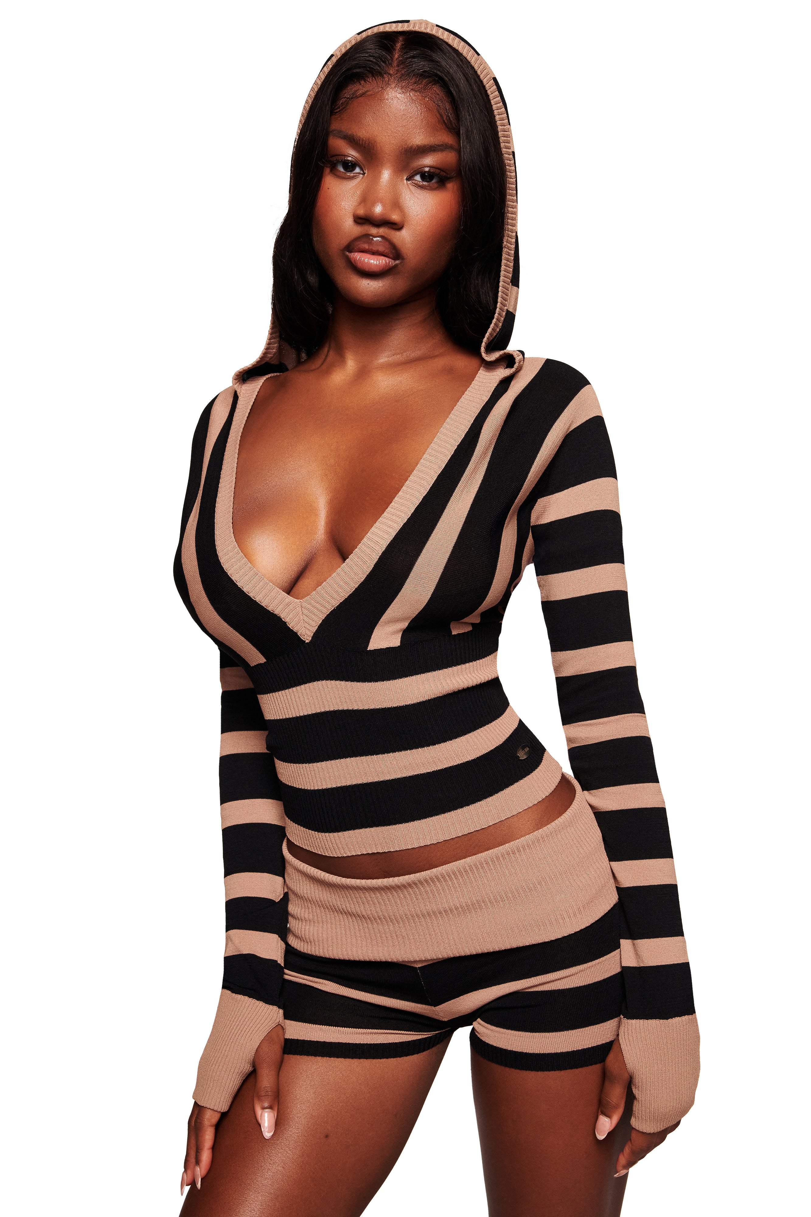 A woman models the I.AM.GIA SUZI SWEATER in black and tan stripe with a deep V-neck and cropped fit, paired with matching high-waisted shorts, against a white background.
