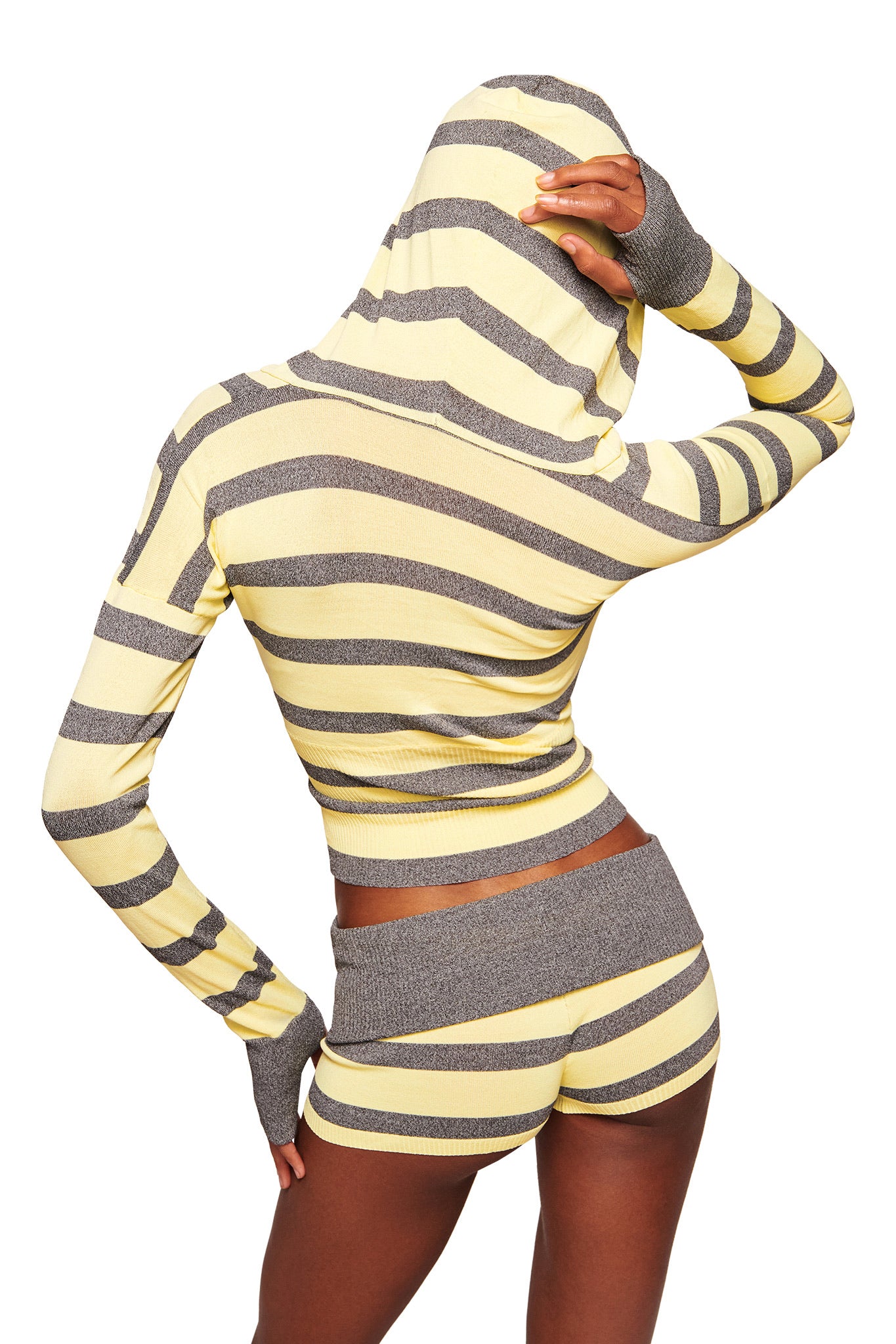 A person, seen from the back with one hand on their head and the hood up, wears the I.AM.GIA SUZI SWEATER - YELLOW AND GREY STRIPE set against a white background.
