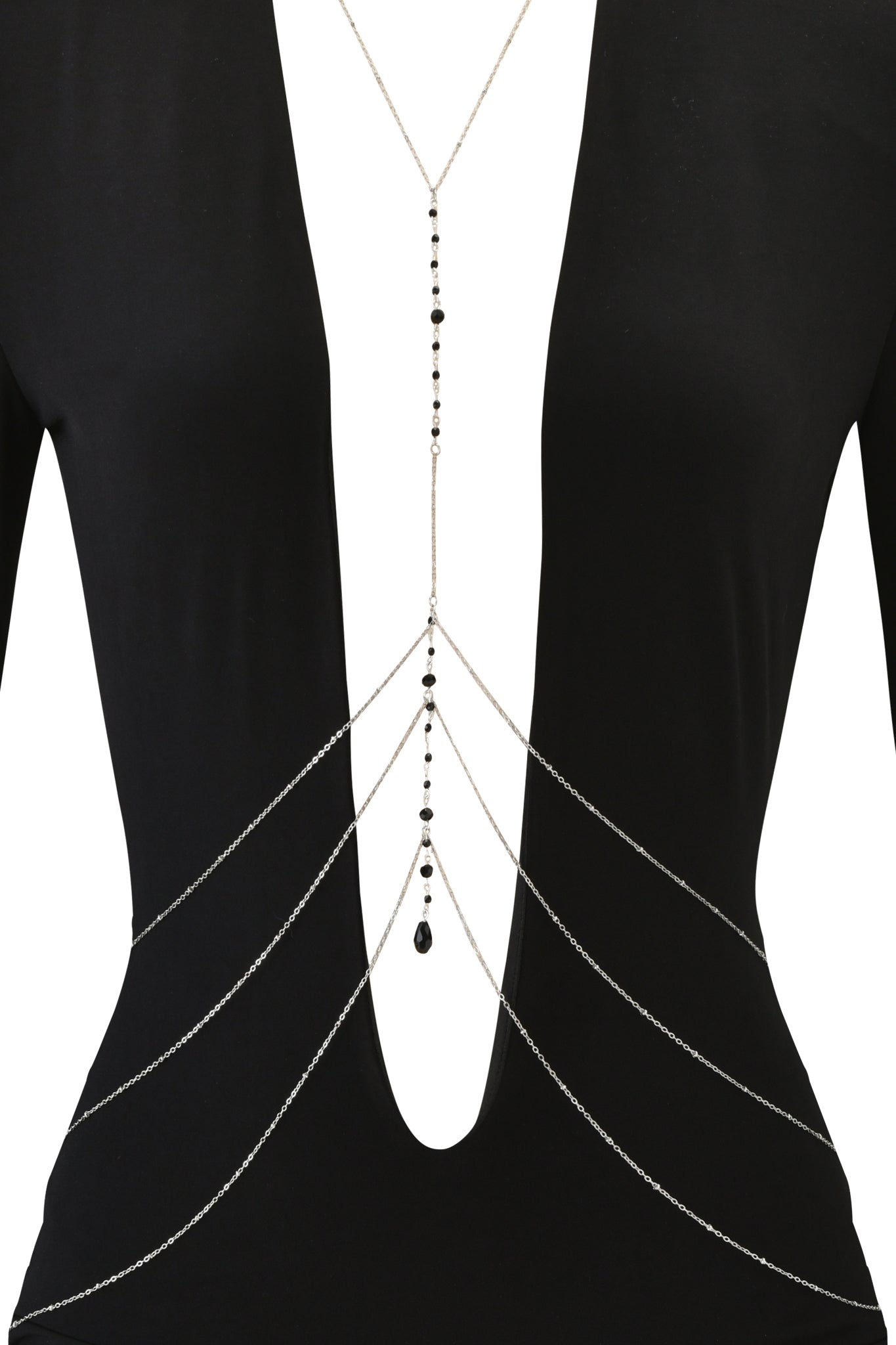 A person wearing the I.AM.GIA PADMA MINI DRESS in black with a deep V-neck, styled with a layered silver body chain featuring small black beads and a teardrop-shaped pendant at the lowest point.