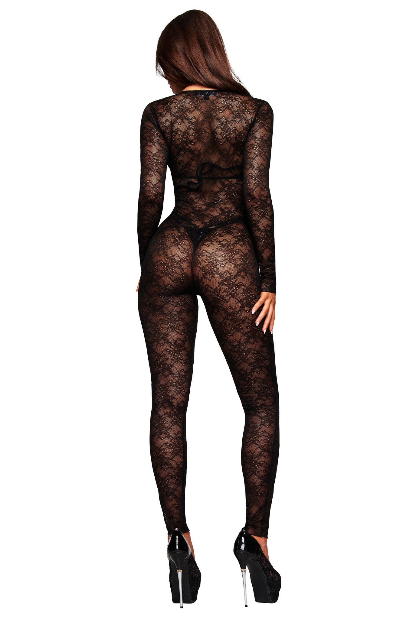 A woman faces away, wearing the I.AM.GIA TIGRA CATSUIT - BLACK, a sheer lace, bodycon catsuit with long sleeves. Her hair is down and she wears high heels, elegantly silhouetted against a plain white background.